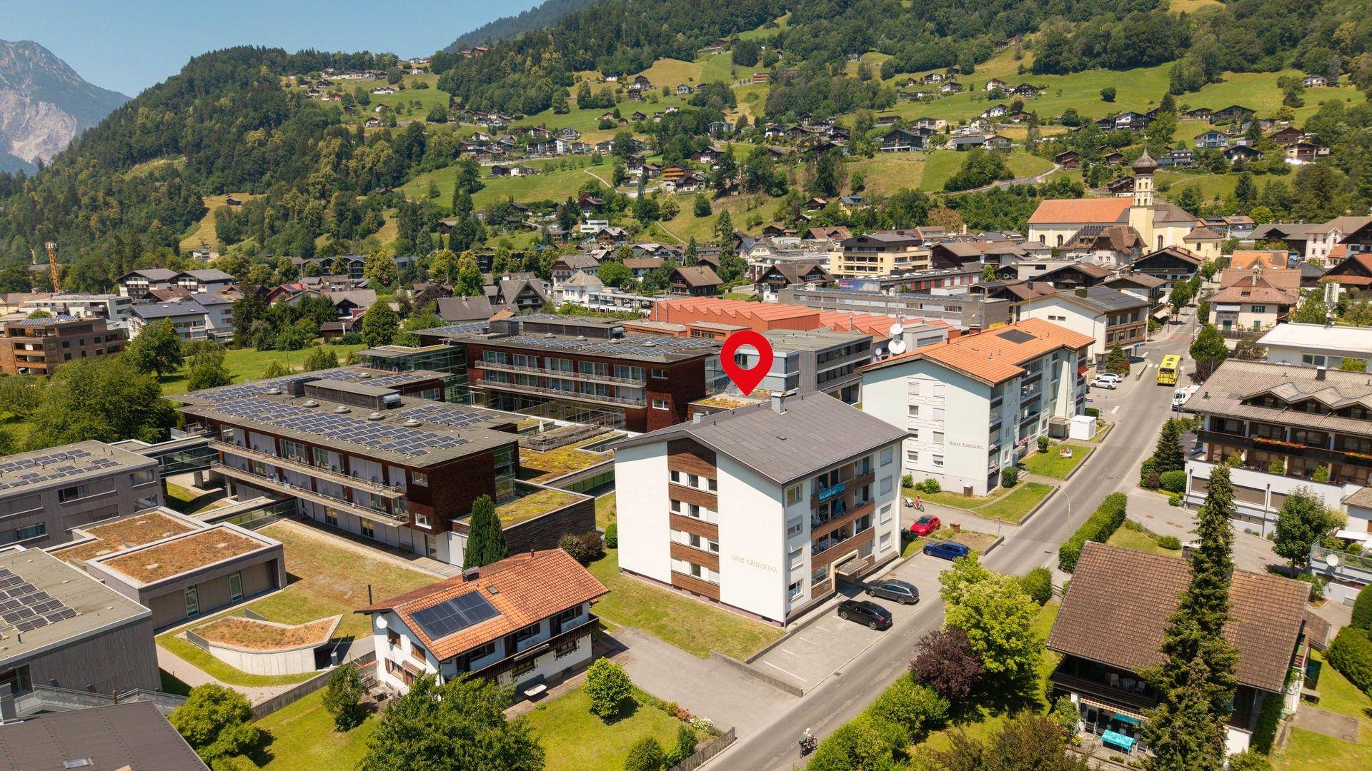 Luftaufnahme des Gebäudes in einer Wohngegend mit Bergblick und umliegenden Häusern.