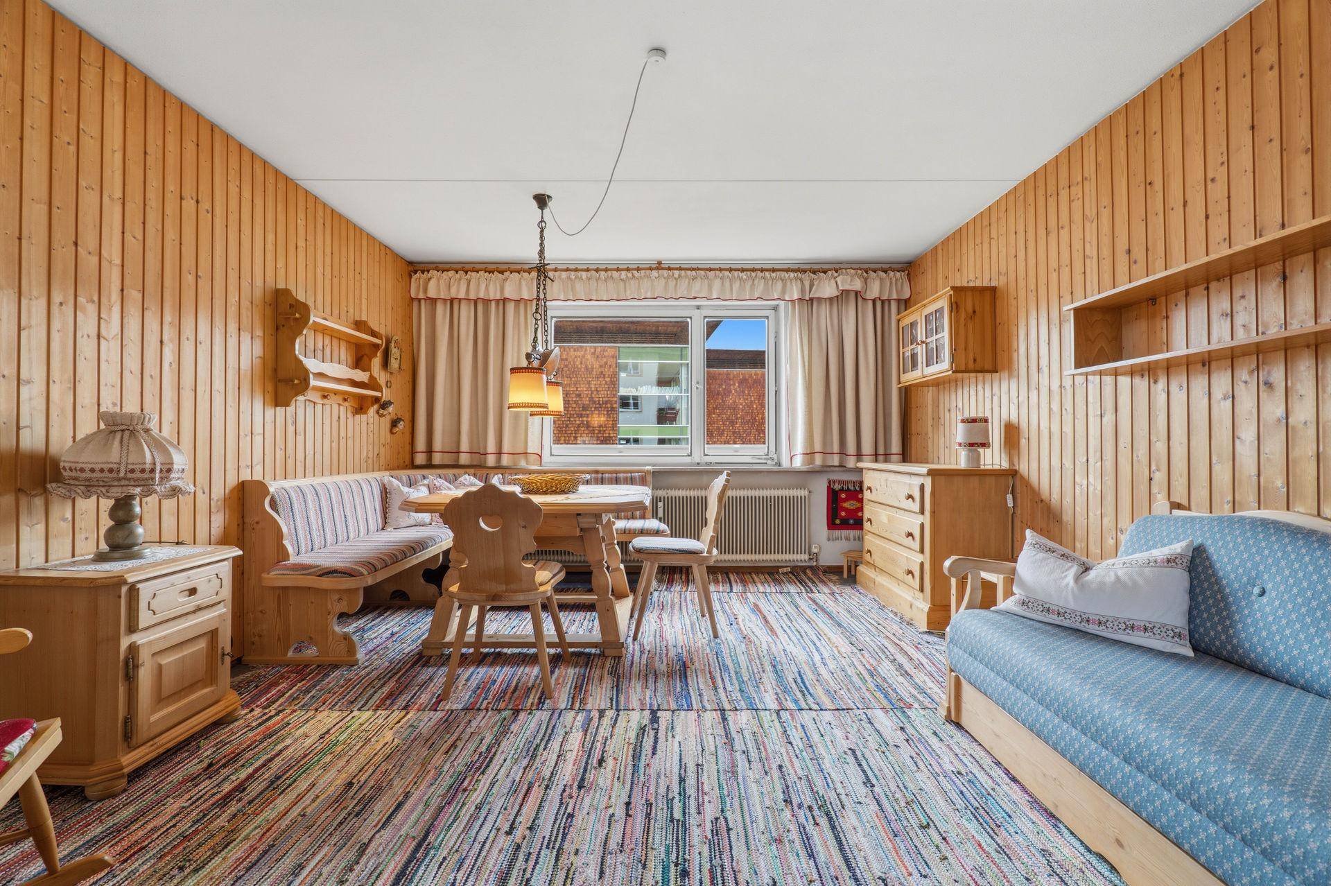 Geräumiger Wohn- und Essbereich im traditionellen Stil mit Holztäfelung und farbenfrohem Teppich.