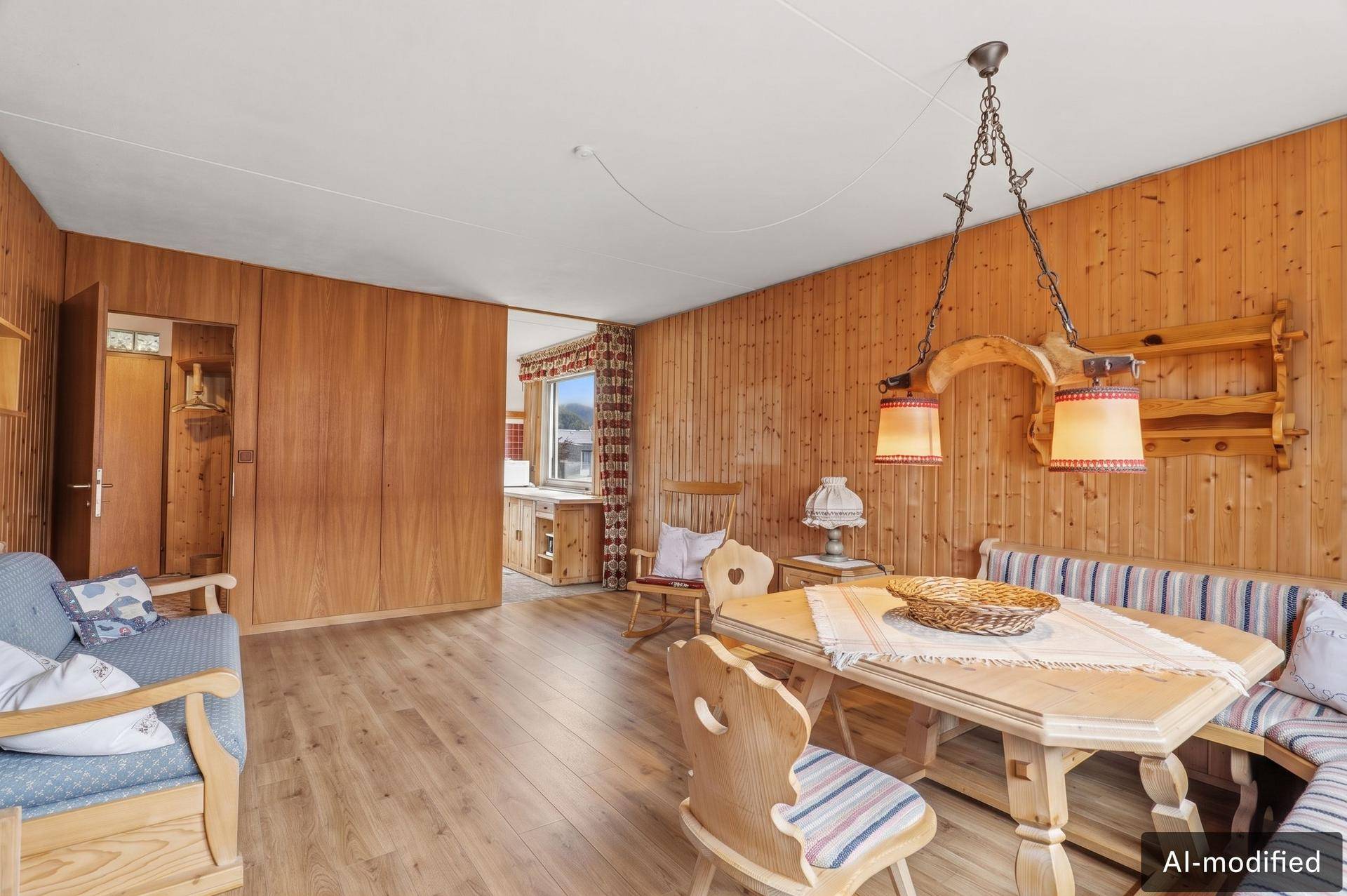 Wohn- und Essbereich im alpinen Stil mit Holztäfelung und neuem Laminatboden.
