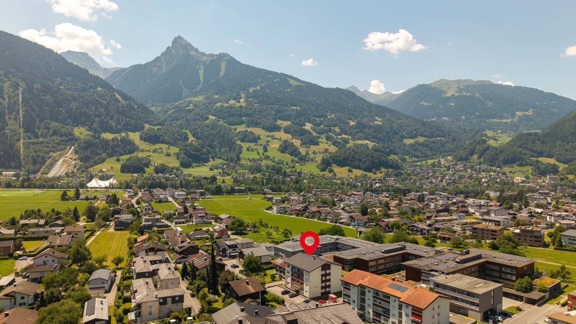 Weitläufige Luftaufnahme der Wohngegend mit Bergblick und vielen Grünflächen.