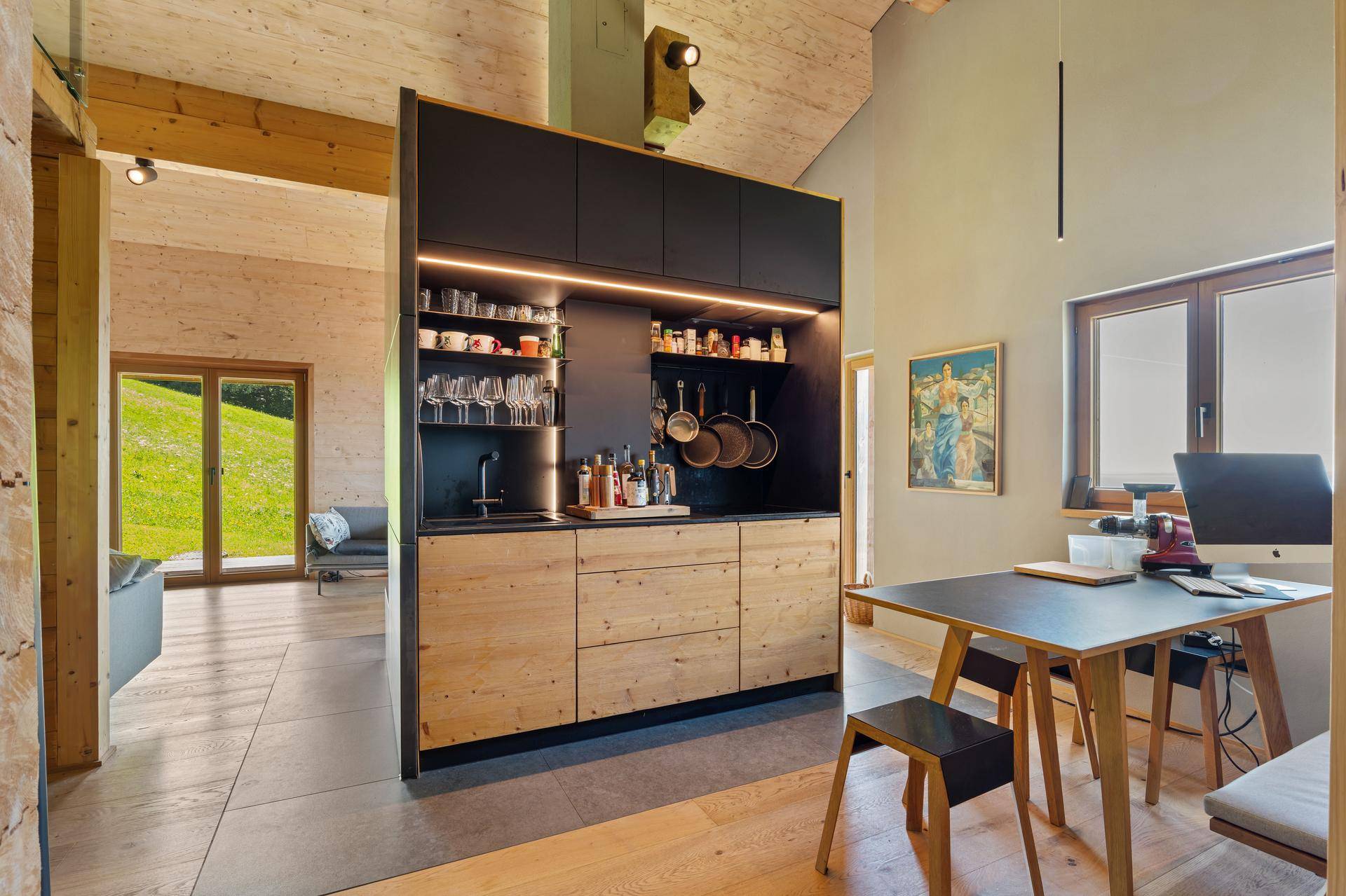 Moderne Küchenzeile mit Holzelementen und schwarzem Design, offen zum Essbereich und Wohnzimmer.