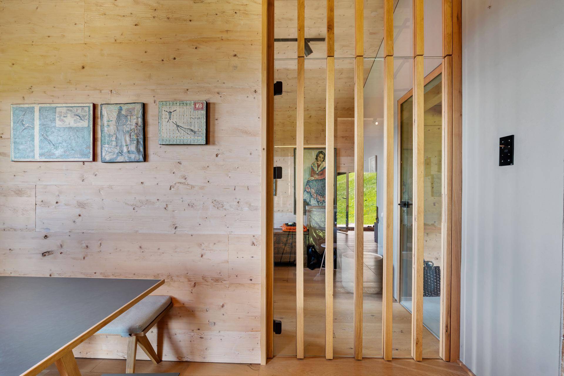 Heller Flur mit Holzwänden und einer modernen Holzlamellenwand, die den Raum strukturiert.