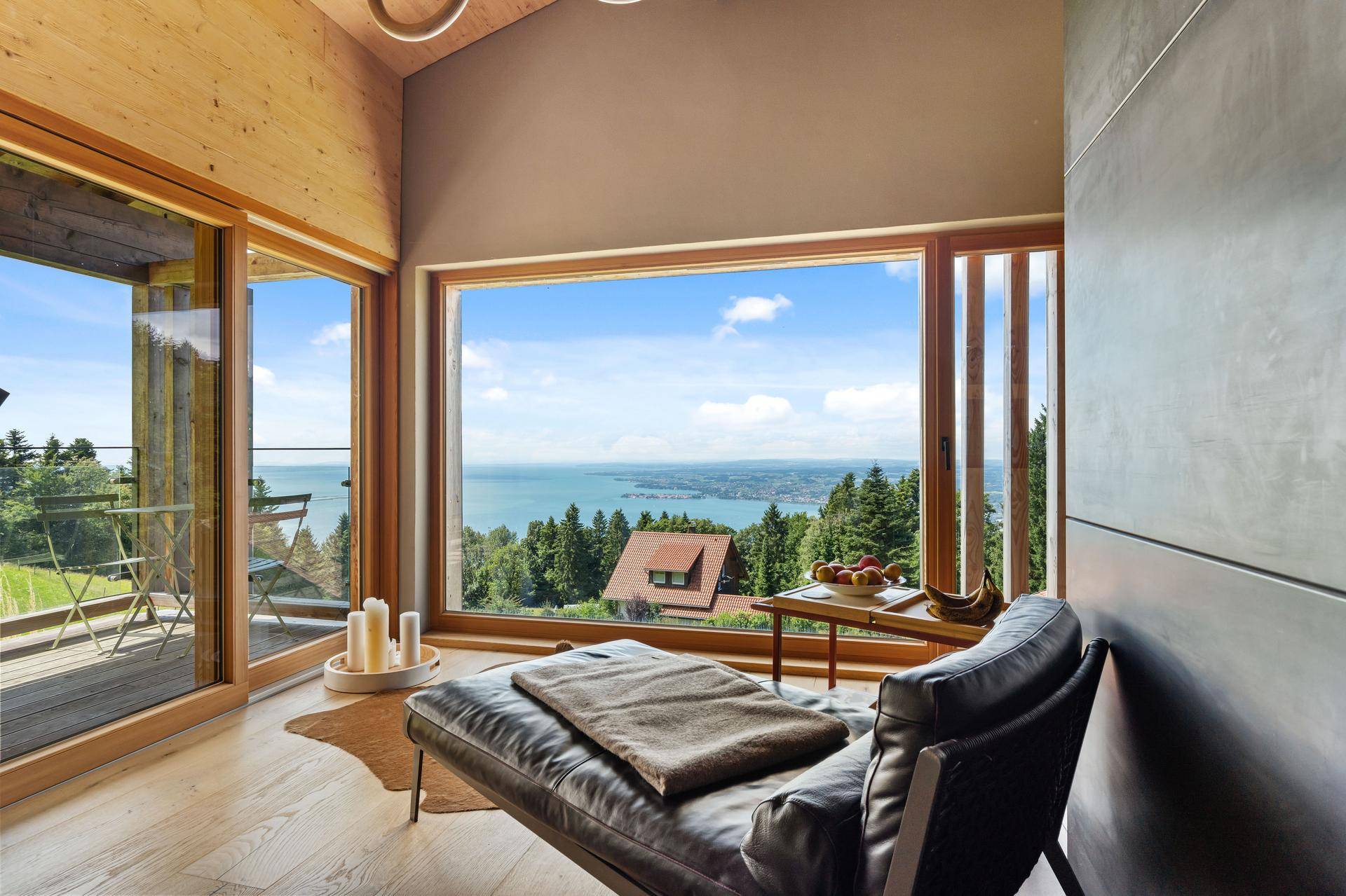 Gemütlicher Liegebereich mit großen Fenstern, die einen atemberaubenden Blick auf den See und die Landschaft bieten.