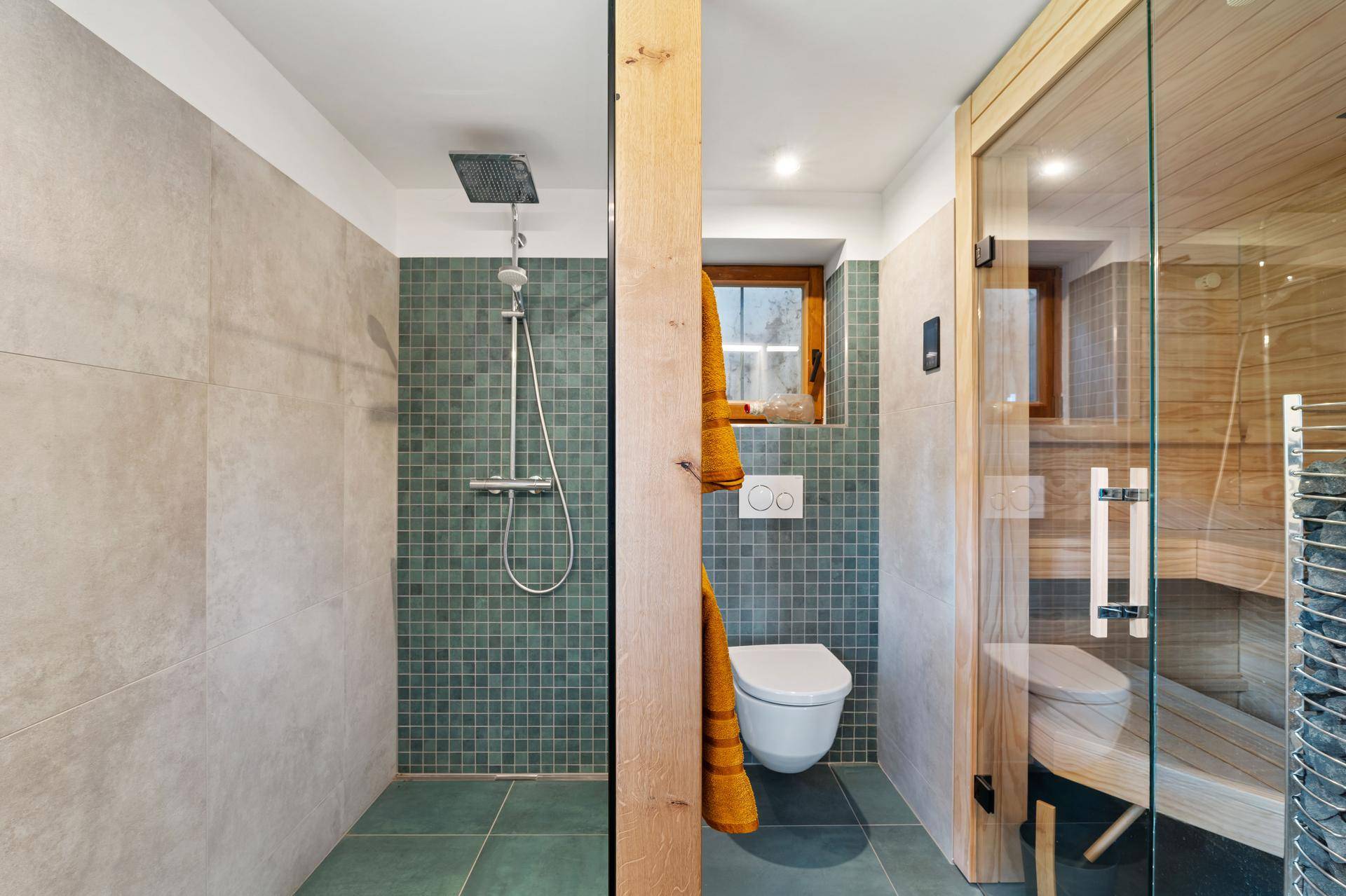 Modernes Badezimmer mit begehbarer Dusche, Wand-WC und Sauna, ausgestattet mit grünen Mosaikfliesen.