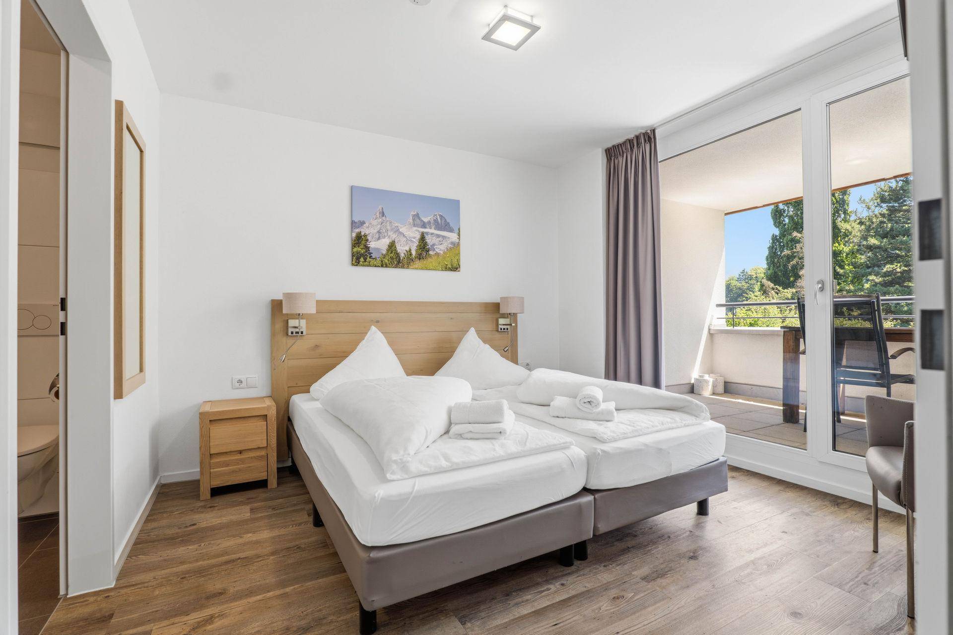 Helles Schlafzimmer mit zwei Einzelbetten und direktem Zugang zum Balkon.