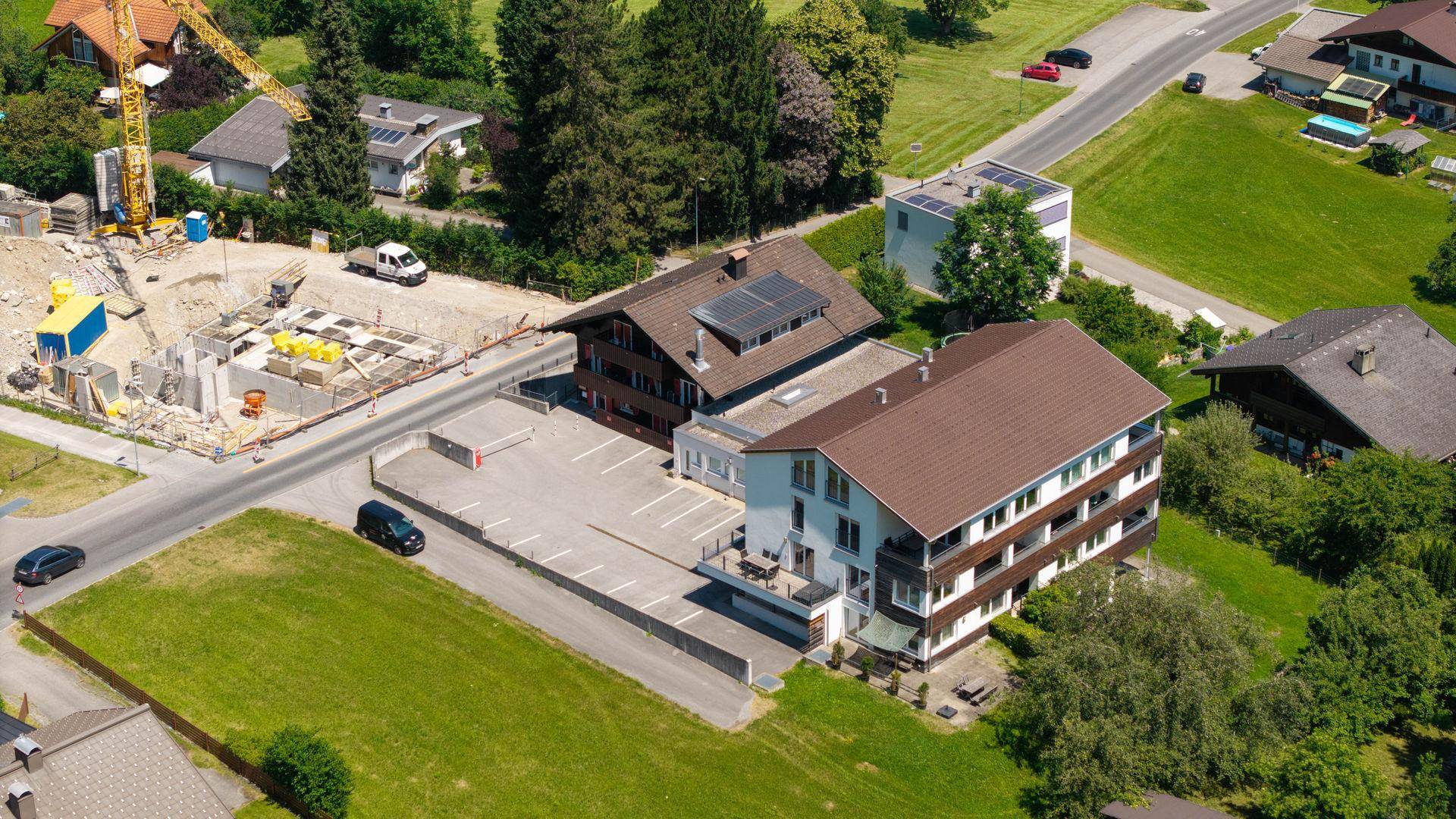 Luftaufnahme des Gebäudes mit Parkplätzen und umliegender Landschaft.