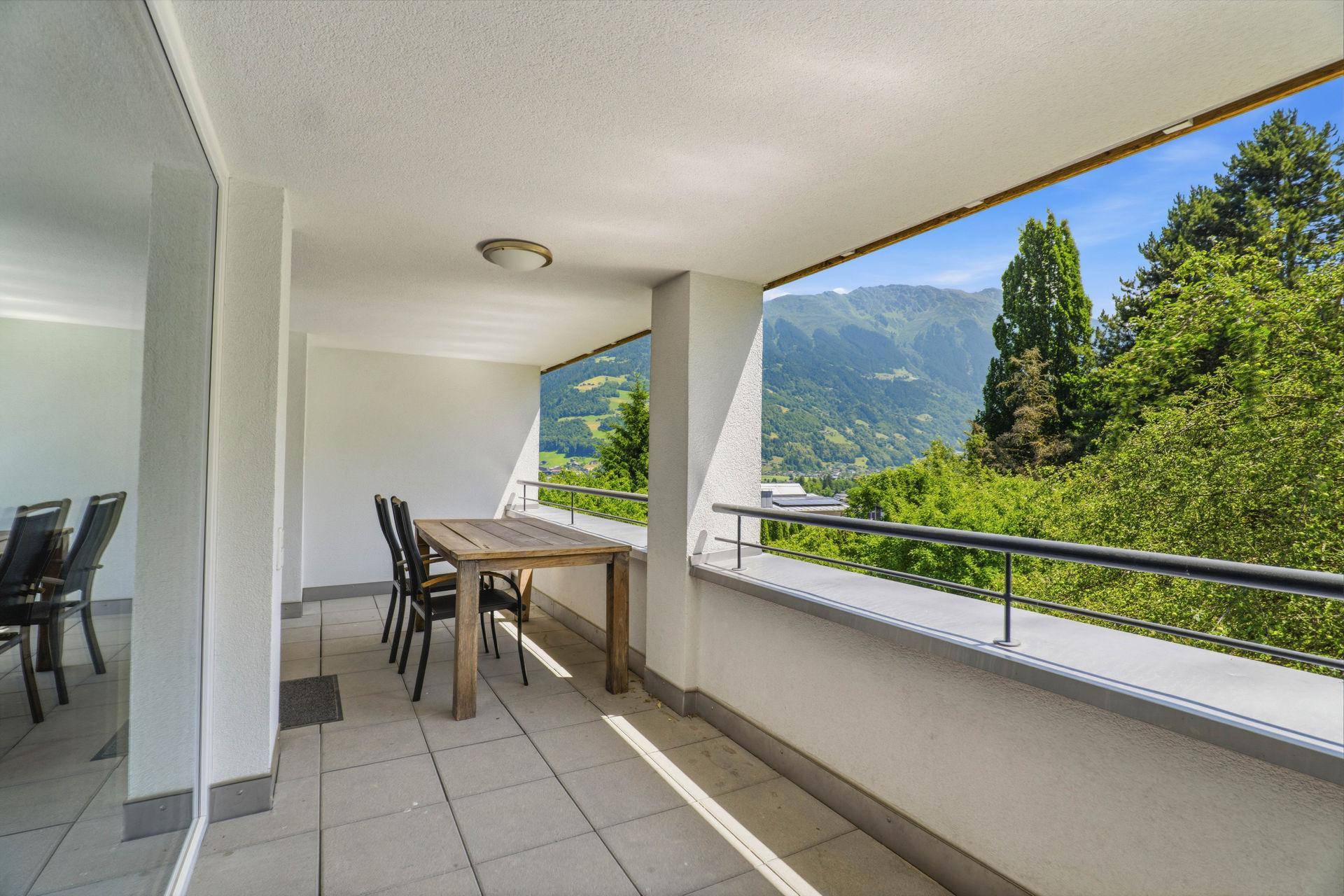Geräumiger Balkon mit Esstisch und Stühlen, bietet einen weiten Bergblick.