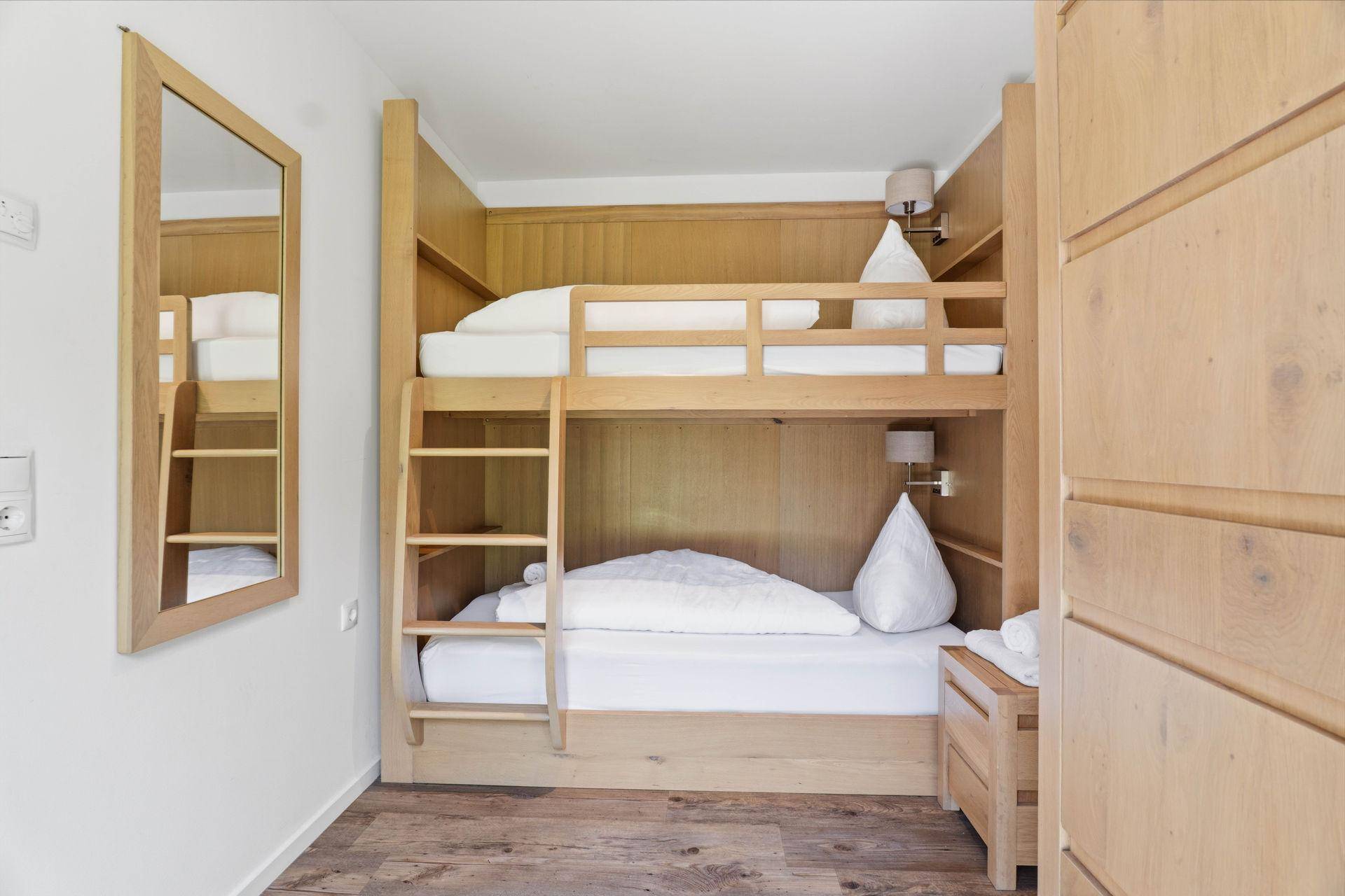 Gemütliches Schlafzimmer mit Etagenbetten und Holzvertäfelung.