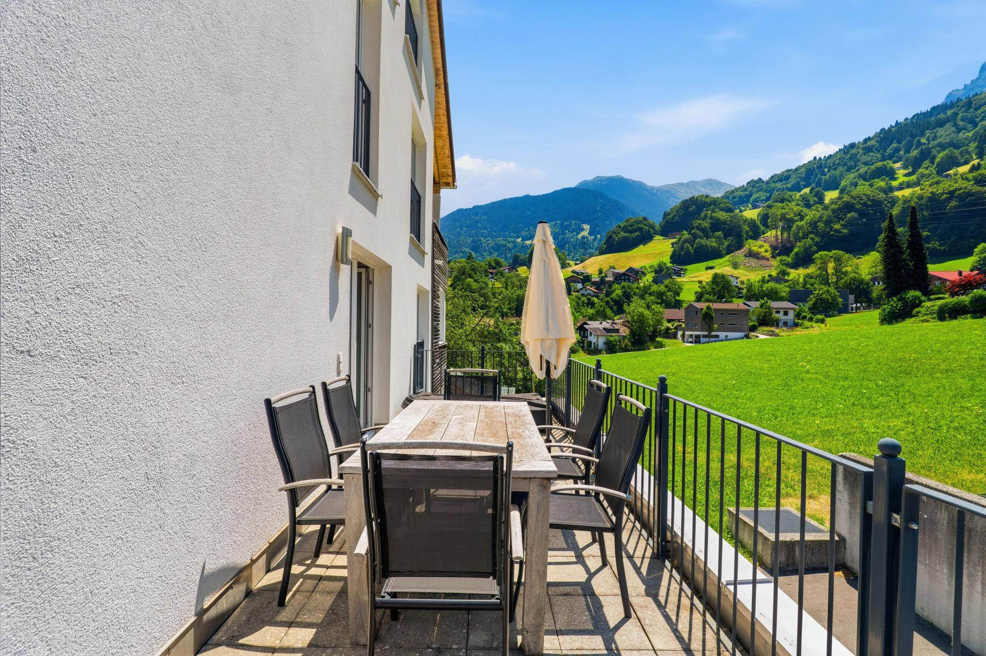 Großer Balkon mit Sitzgelegenheiten und weitem Blick ins Grüne und auf die Berge.
