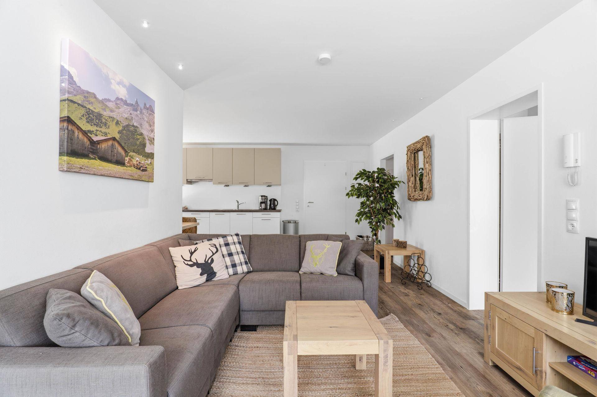 Geräumiges Wohnzimmer mit großem Sofa und Blick auf den Küchenbereich.