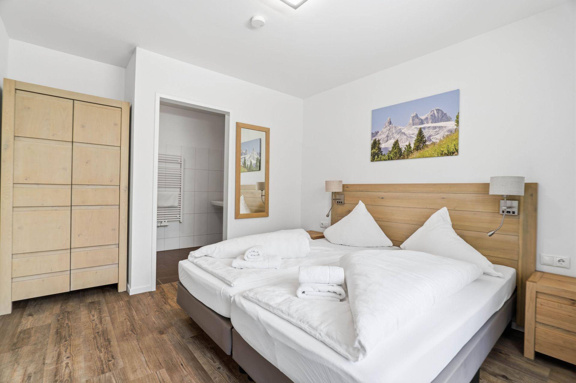 Komfortables Schlafzimmer mit Holzschrank und angrenzendem Badezimmer.