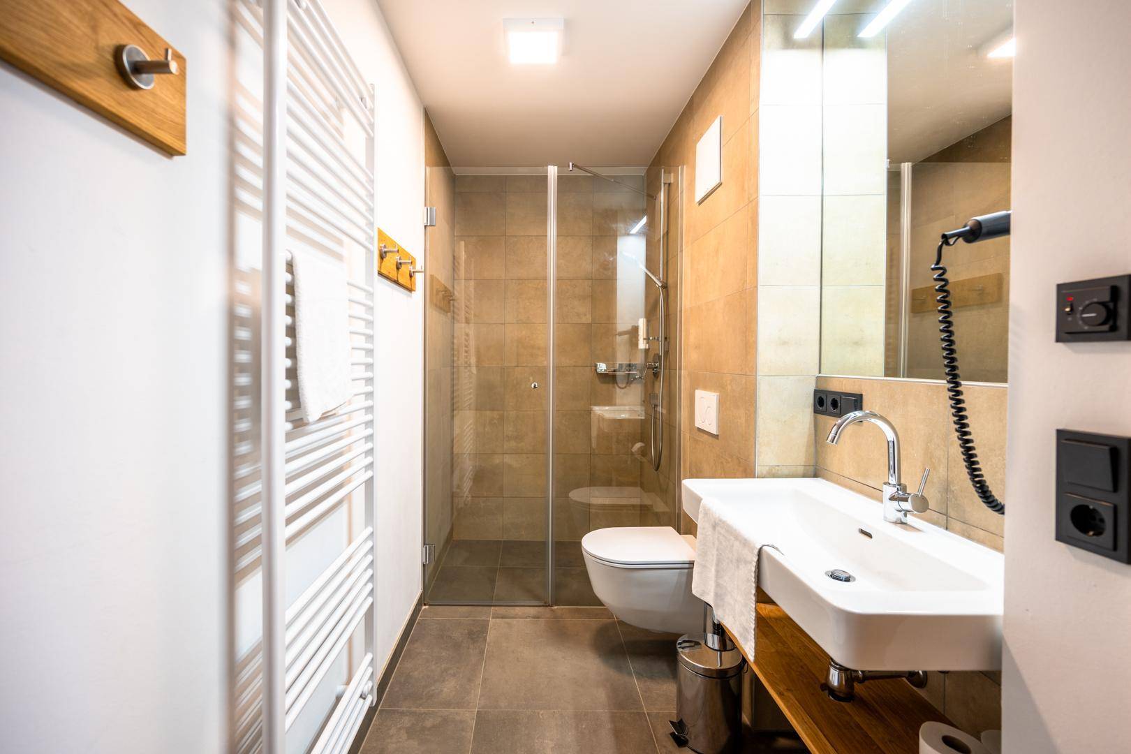 Modernes Badezimmer mit Dusche, beheiztem Handtuchhalter und großem Spiegel.