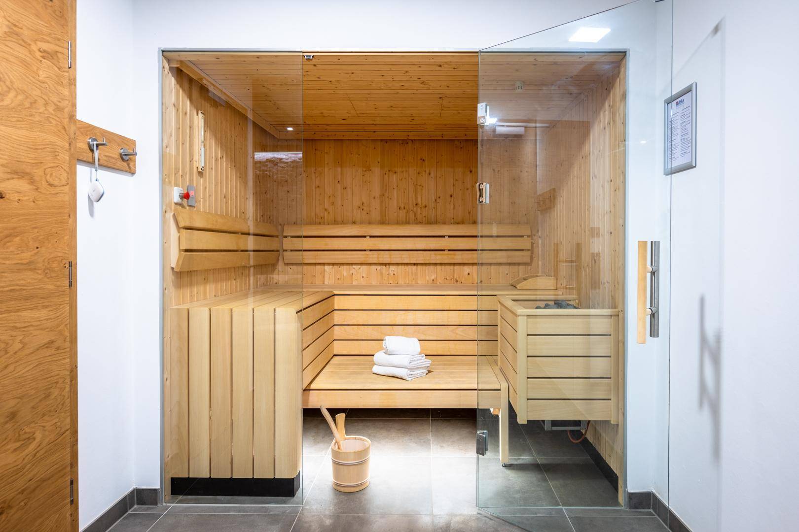 Geräumige Holzsauna mit Glasfront, Bänken und traditionellem Saunaofen.