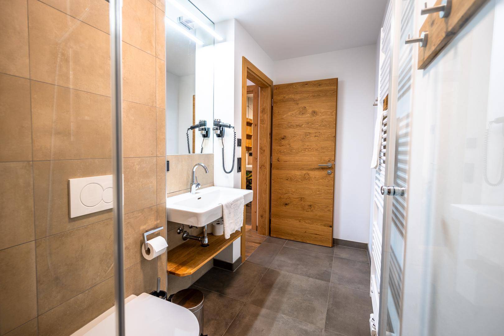 Modernes Badezimmer mit Dusche, Waschbecken und Holztür.