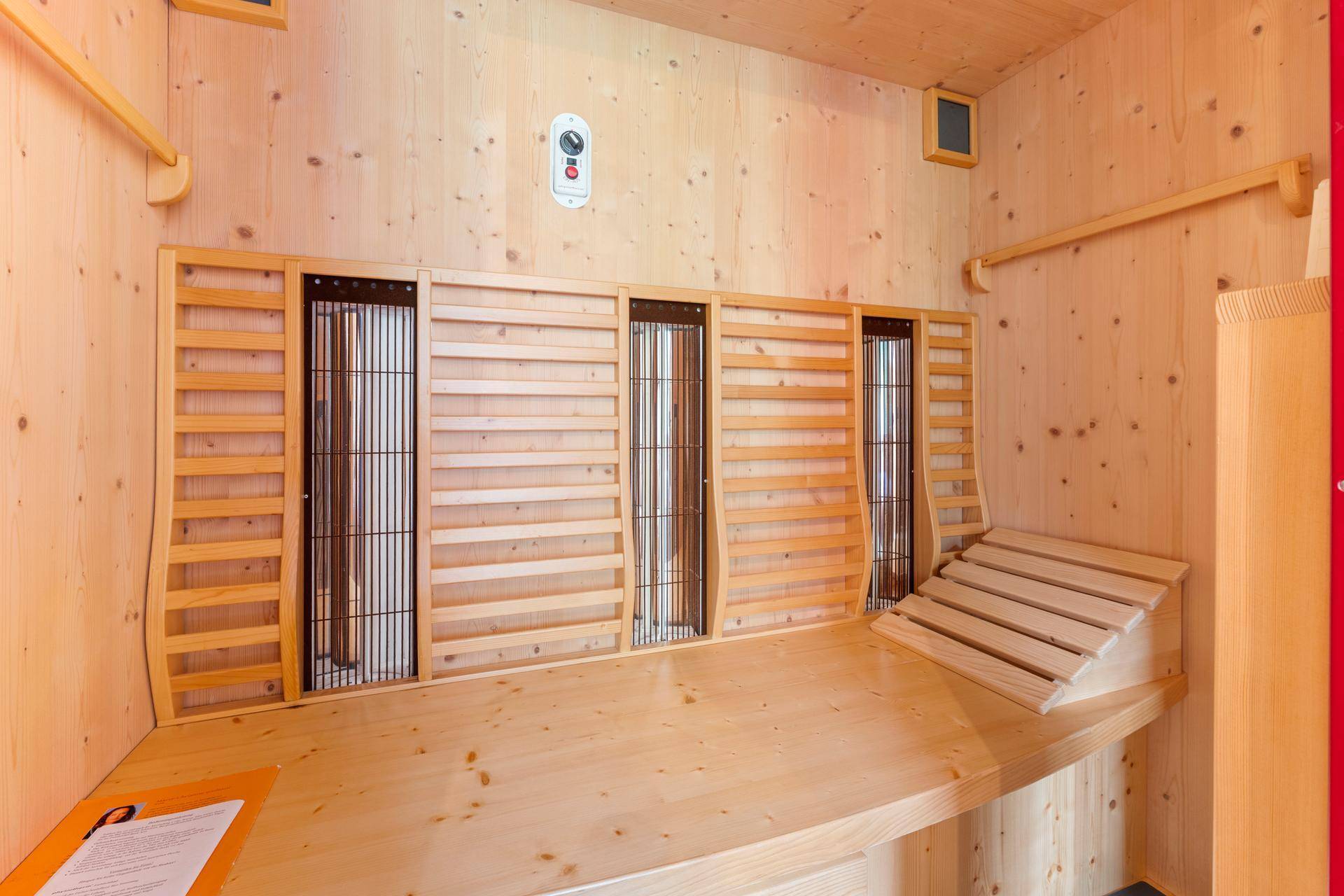 Moderne Infrarotsauna mit Holzverkleidung und bequemen Sitzbänken für Entspannung.