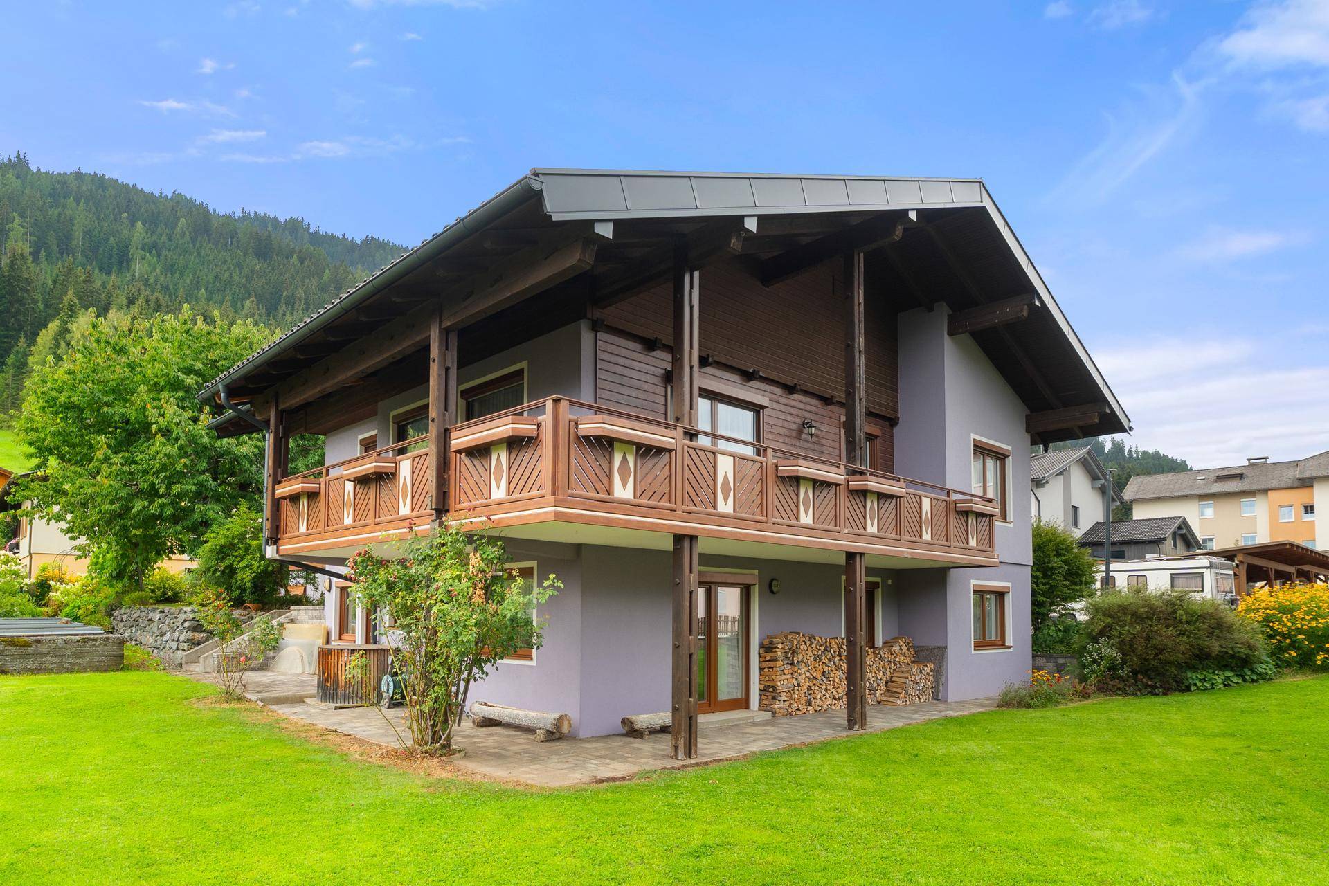 Charmantes Haus im alpinen Stil mit Holzbalkonen und großem Garten in ländlicher Umgebung.
