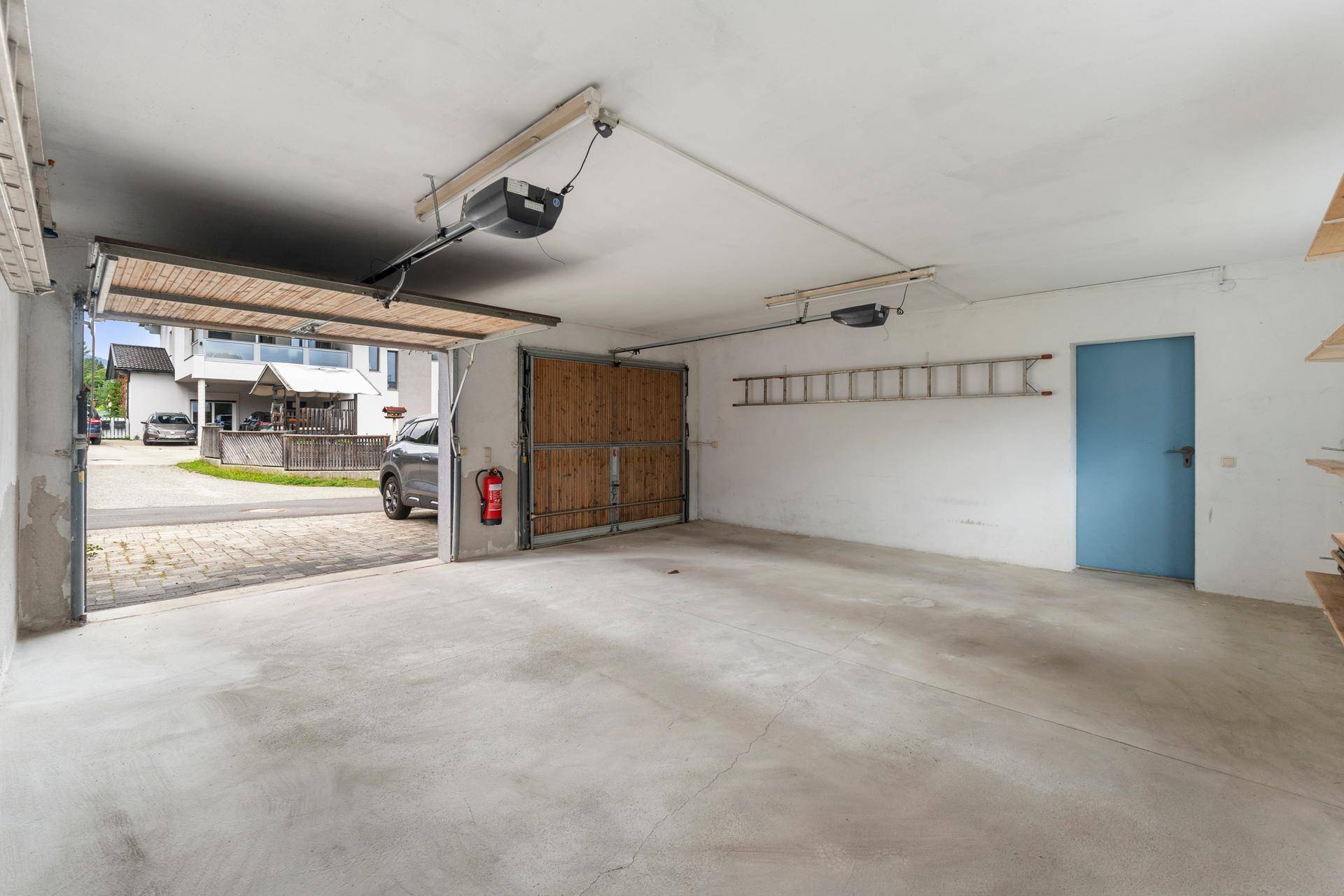 Geräumige Garage mit zwei Toren, Betonboden und direktem Zugang zur Straße.