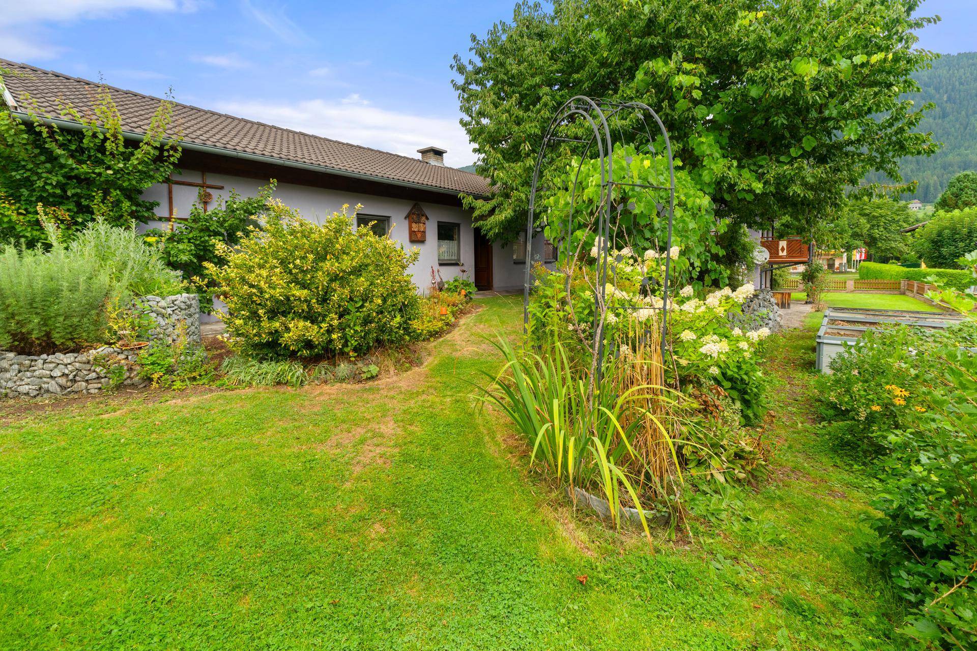 Idyllischer Gartenbereich mit blühenden Pflanzen und einem geschwungenen Pfad zum Haus.