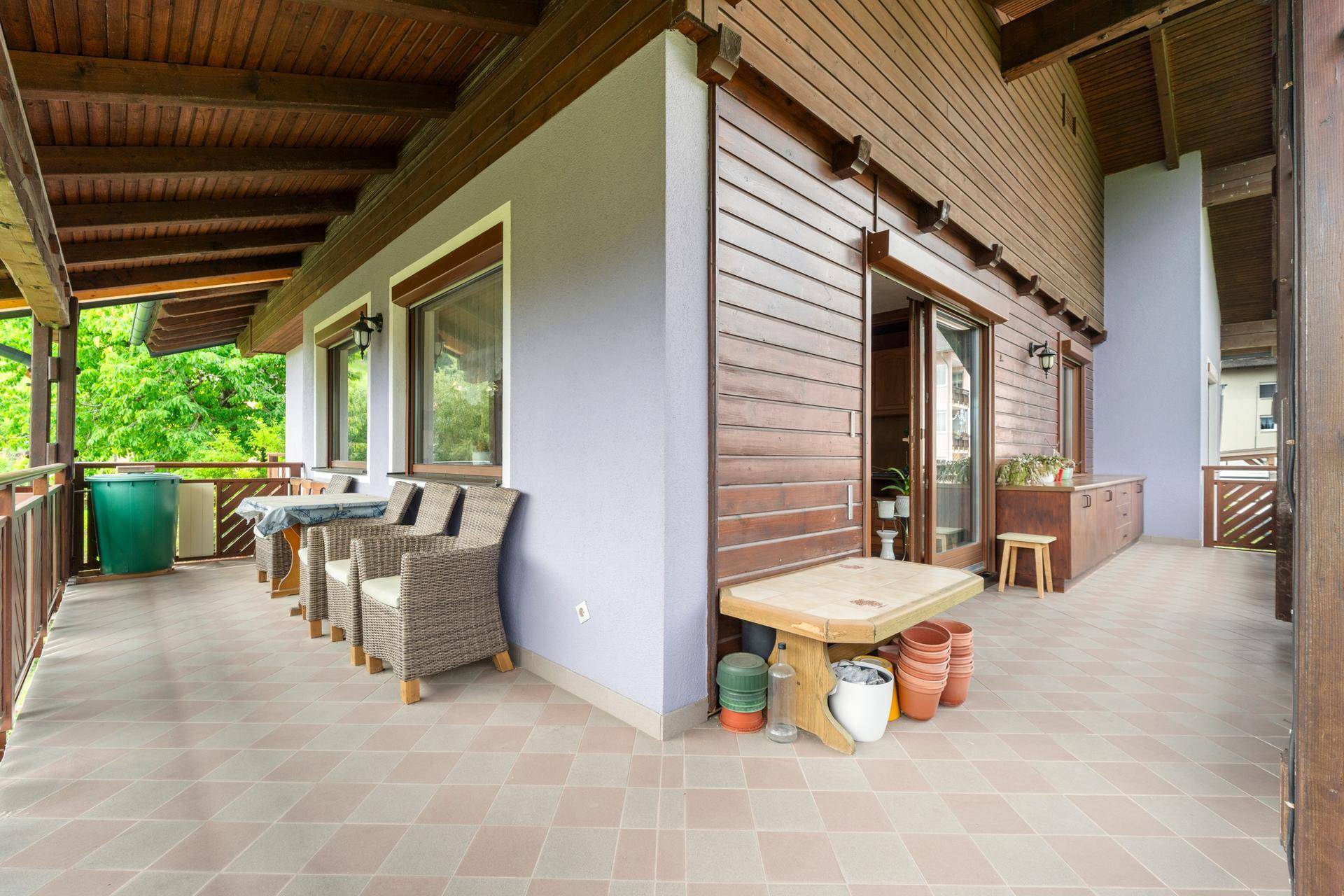 Große überdachte Terrasse mit Fliesenboden und Sitzgelegenheiten, ideal für Mahlzeiten im Freien.