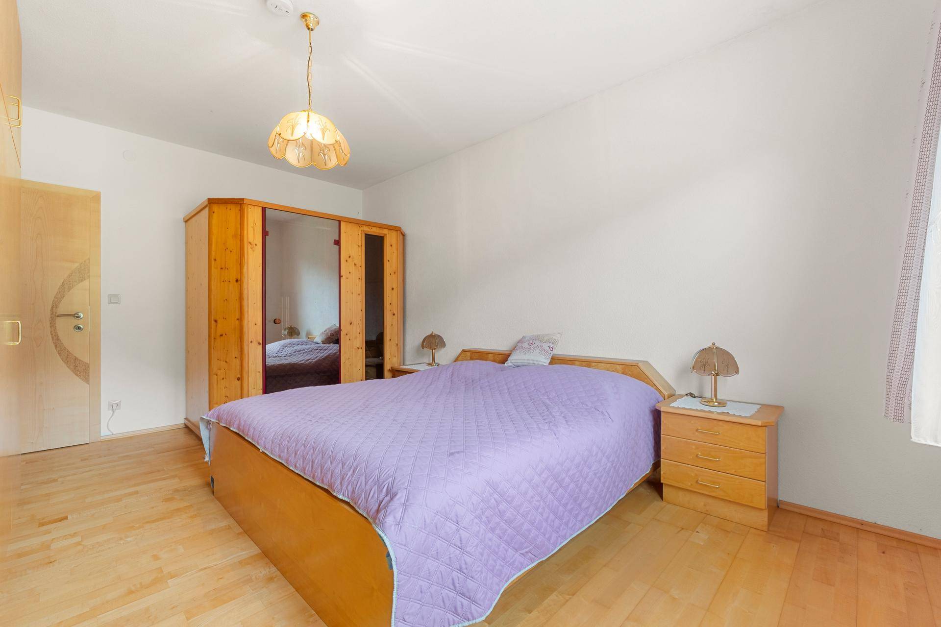 Schlafzimmer mit Holzbett, Nachttischen und Kleiderschrank, hell und funktional eingerichtet.