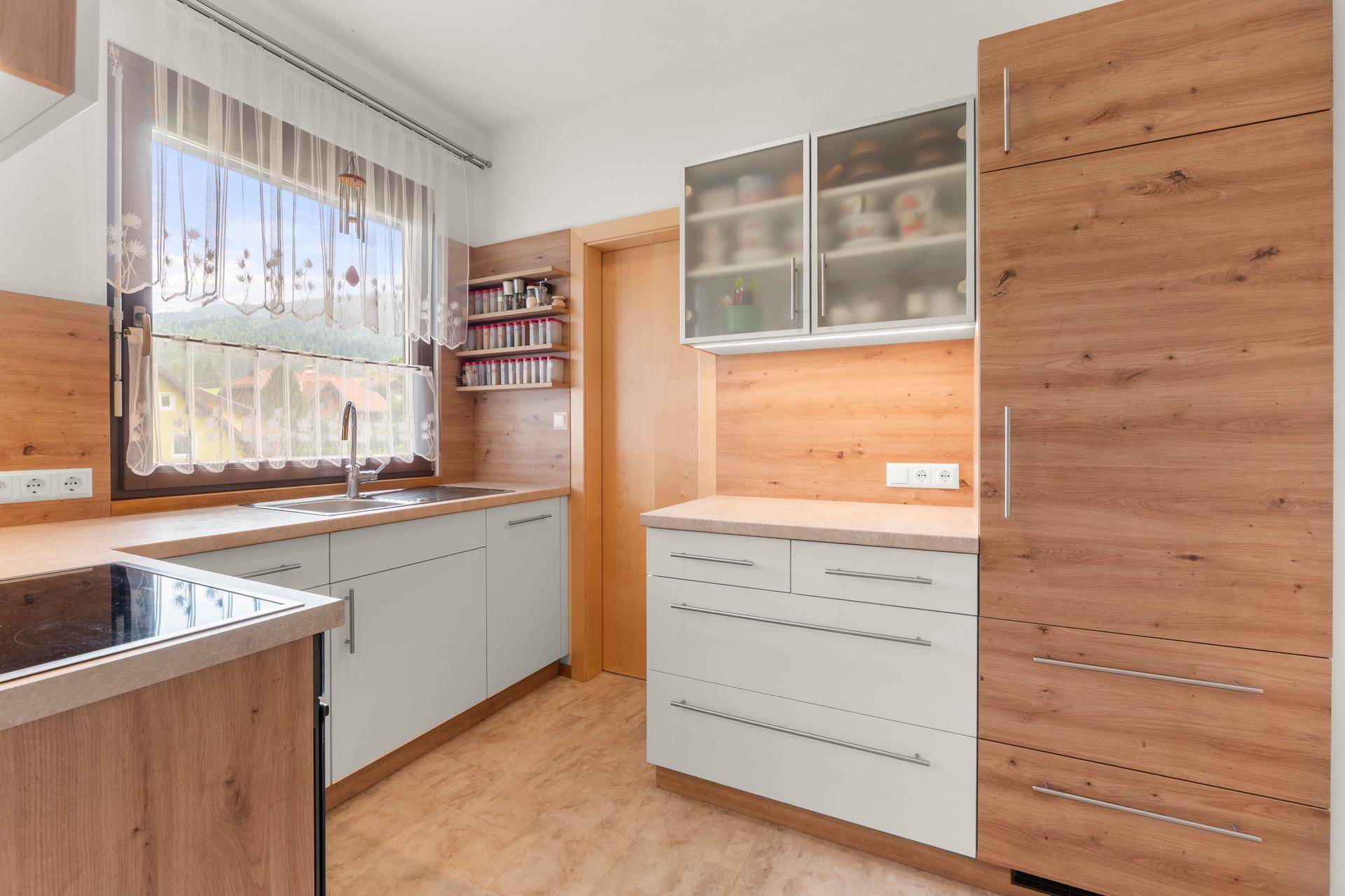 Funktionale Küche mit Holz- und weißen Fronten, Fenster und viel Stauraum.
