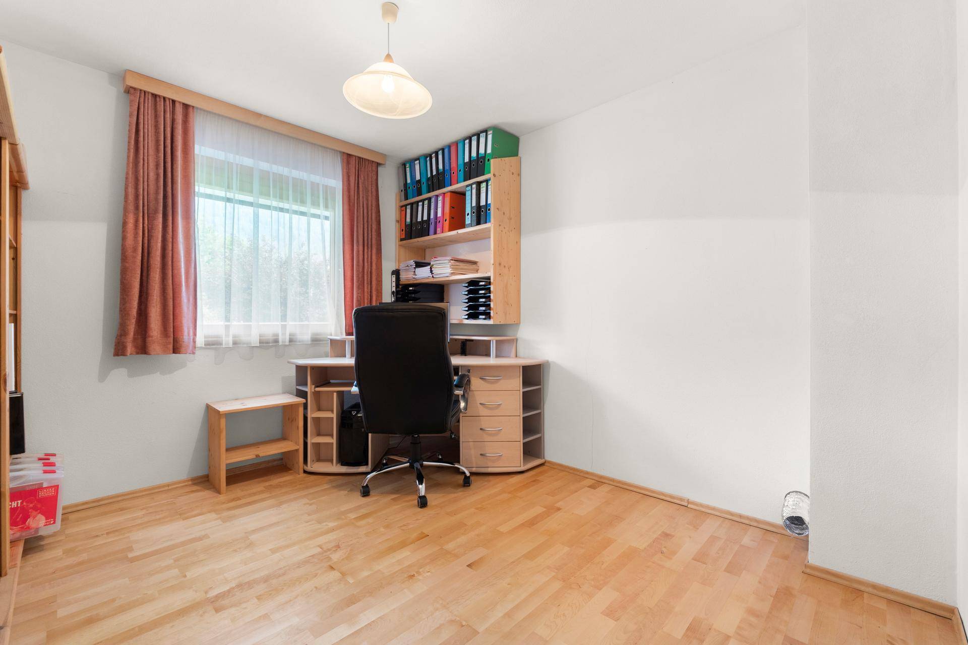 Helles Arbeitszimmer mit Schreibtisch, Regalen und Holzboden.