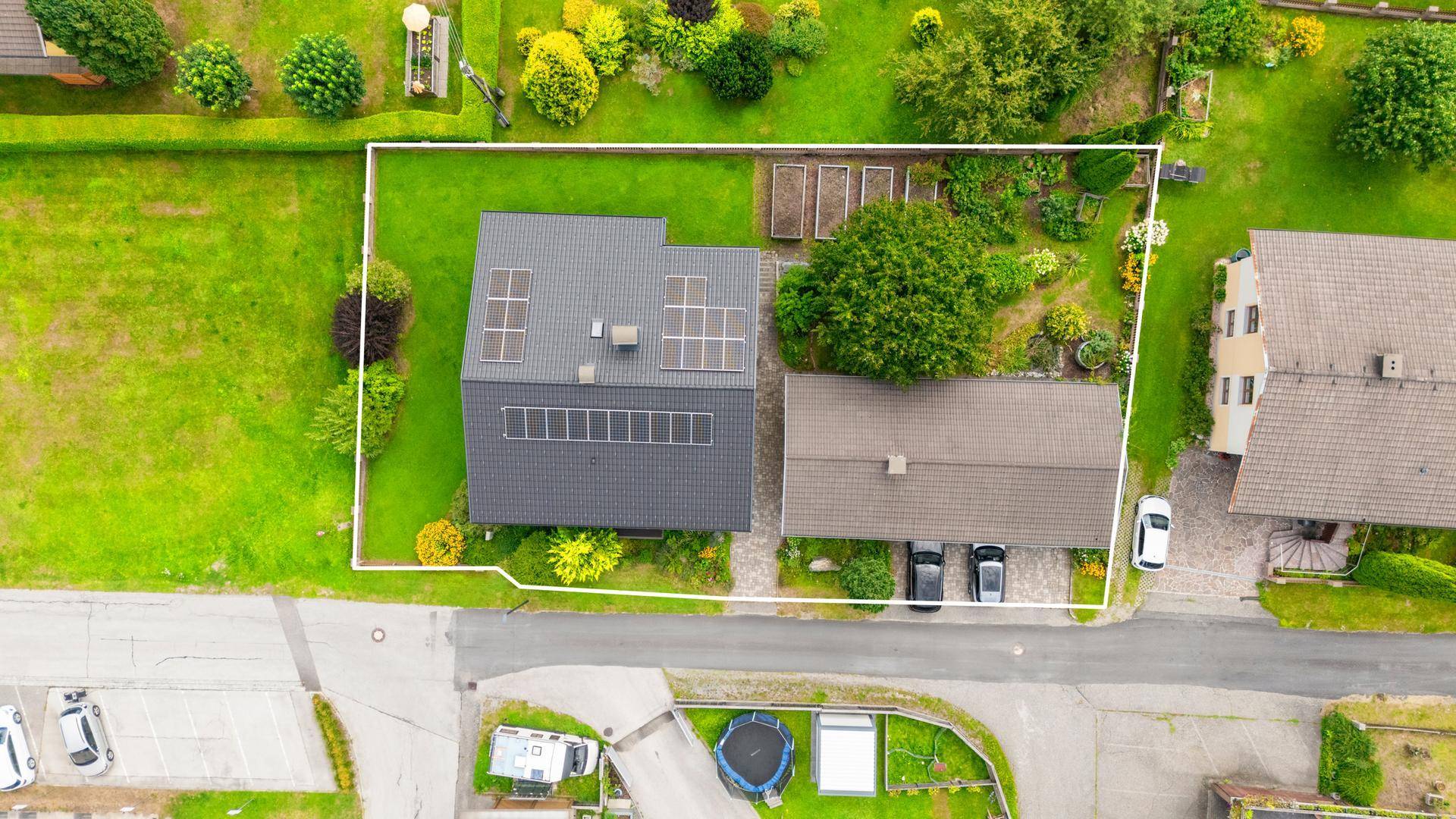 Vogelperspektive des Grundstücks mit Haus, Photovoltaikanlage und Gartenbereich.