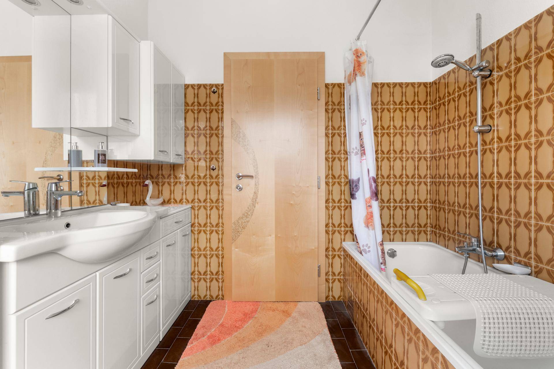 Badezimmer im Stil der 80er Jahre mit braunen Fliesen, Badewanne und Waschbecken.