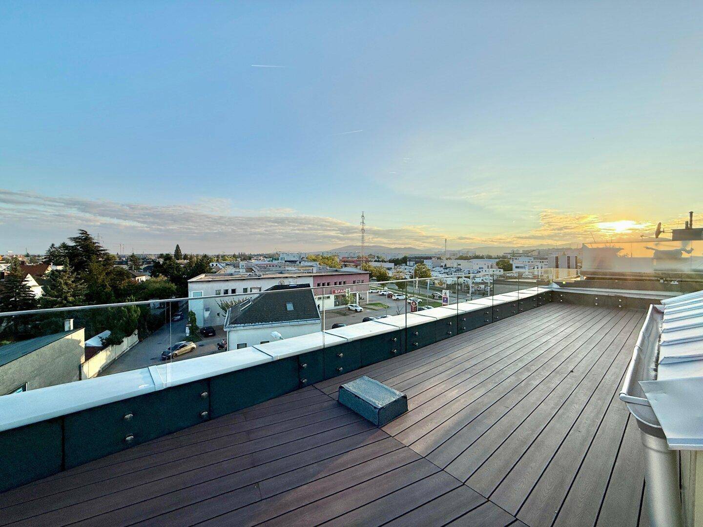 Geräumige Dachterrasse mit Holzboden und Glasgeländer, ideal für Entspannung im Freien.