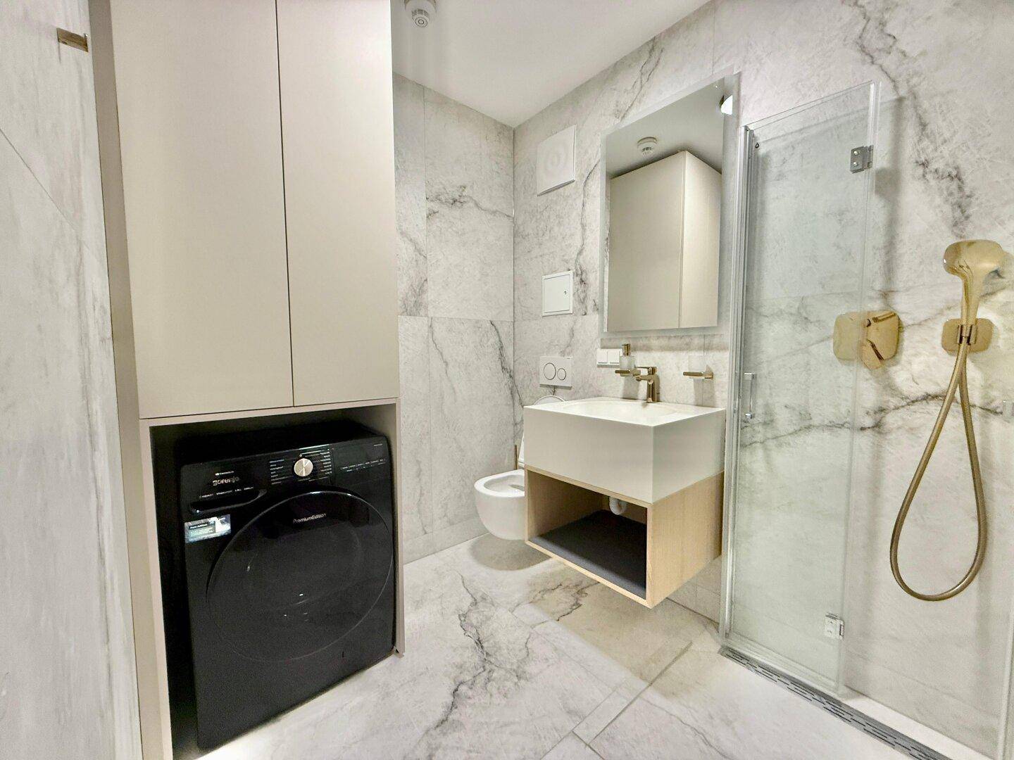 Elegantes Badezimmer mit Marmoroptik, Duschkabine und Waschbecken mit Spiegelschrank.