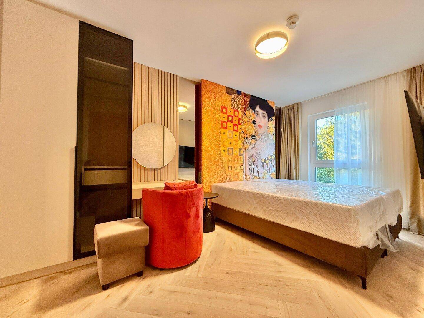Helles Schlafzimmer mit Holzboden, großem Wandbild und Zugang zum Balkon oder zur Terrasse.