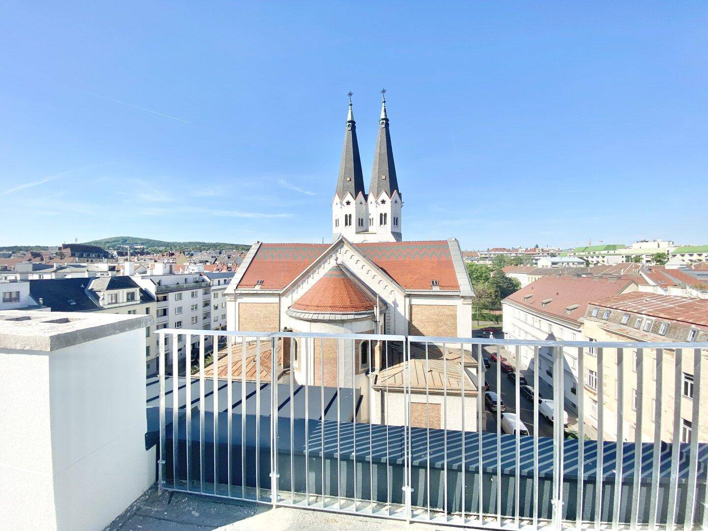 Panoramablick auf eine historische Kirche und die umliegende Stadt von einer erhöhten Position.