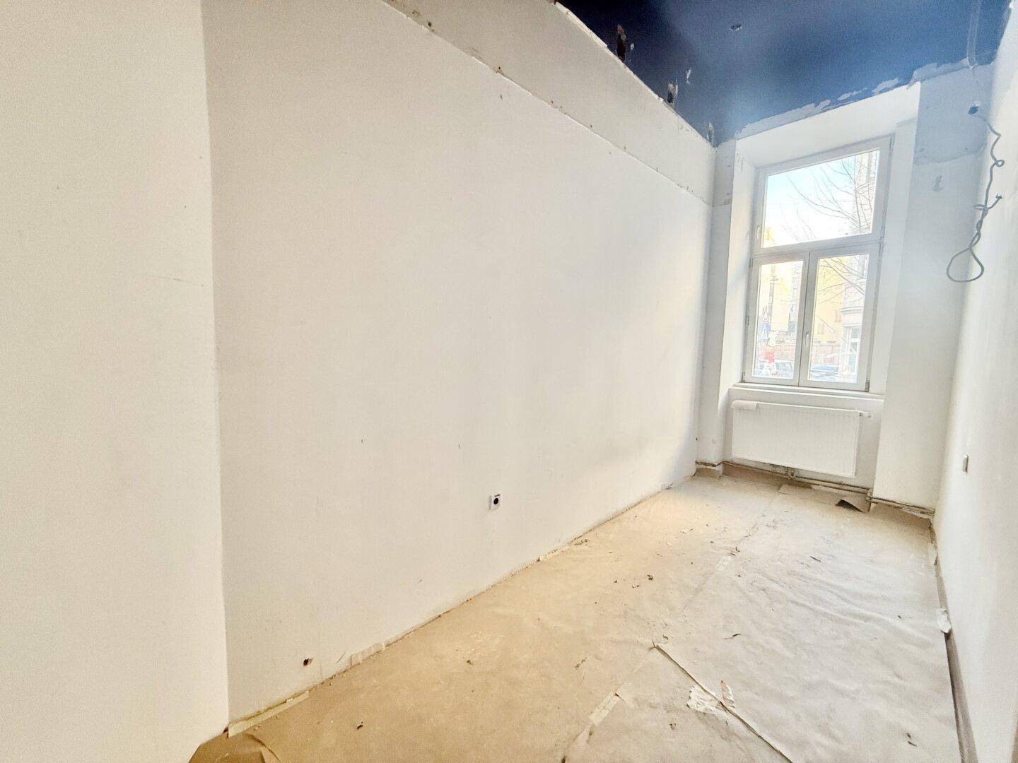 Kleinerer Raum in Renovierung mit weiß gestrichenen Wänden und einem Fenster.