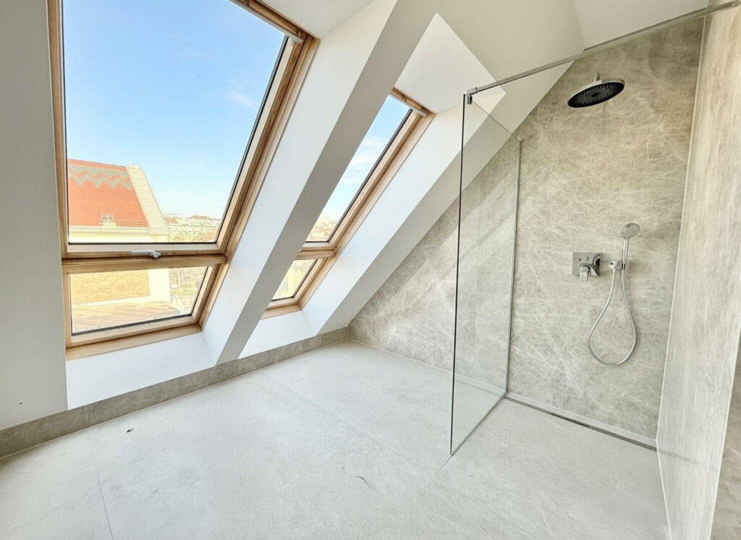 Modernes Badezimmer mit großer begehbarer Dusche, grauen Fliesen und Dachfenstern.