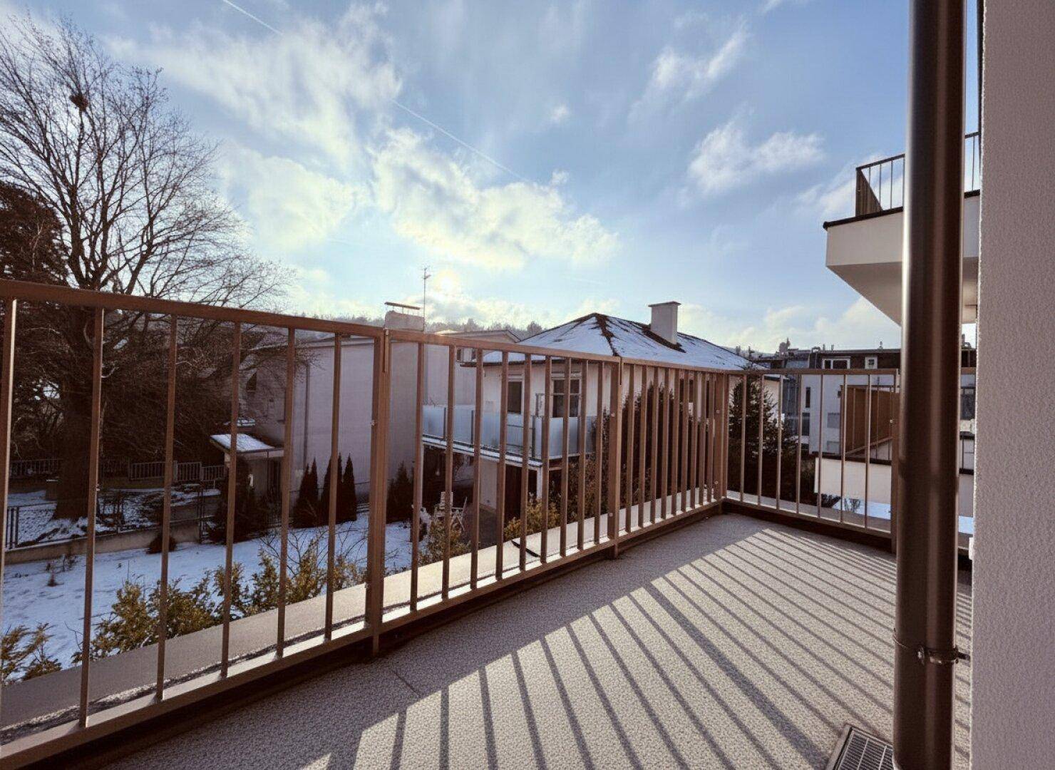 Geräumiger Balkon mit Metallgeländer und Blick auf die verschneite Nachbarschaft im Winter.