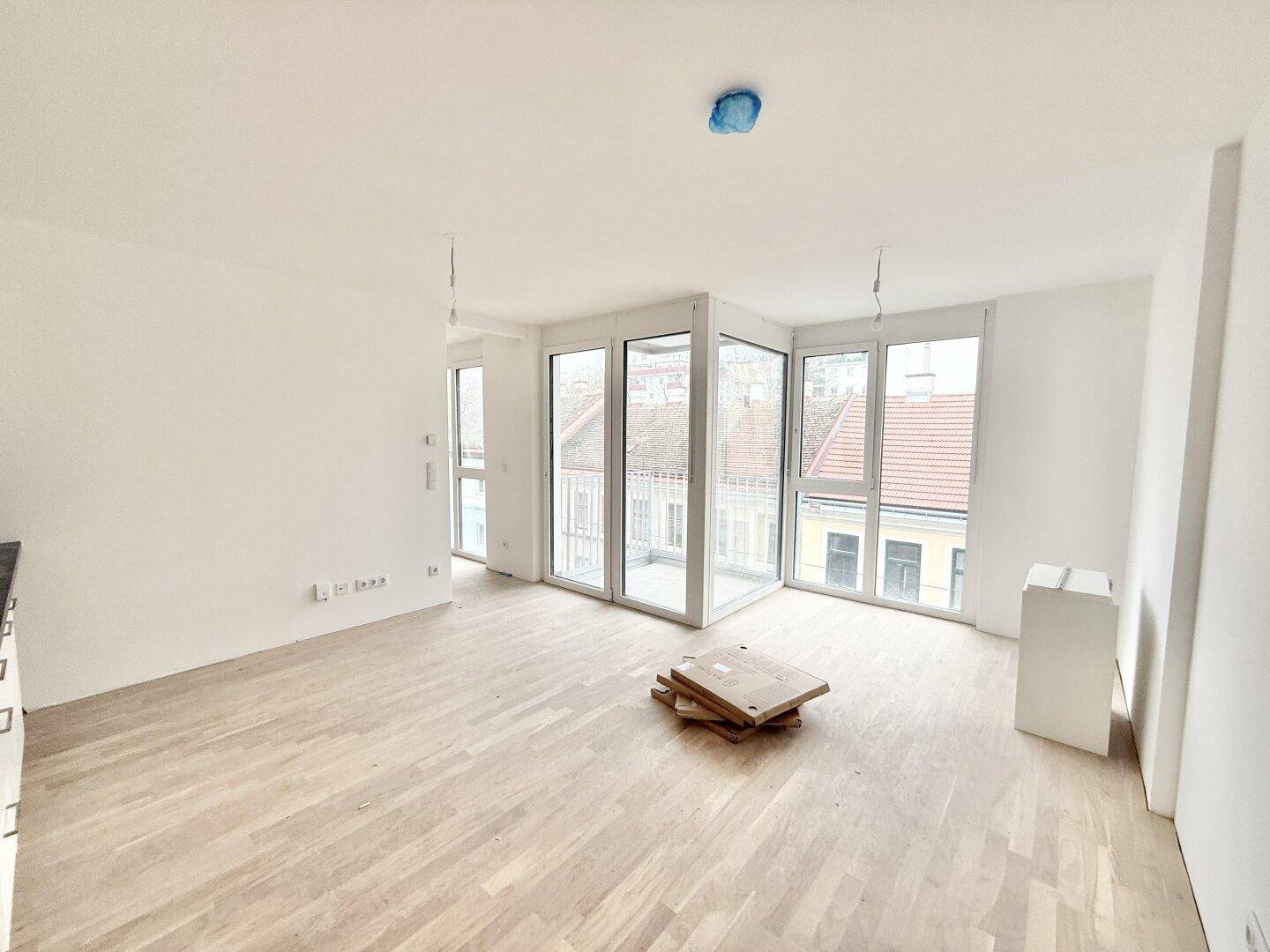 Heller, unmöblierter Wohnbereich mit Parkettboden und Zugang zu einem Balkon.