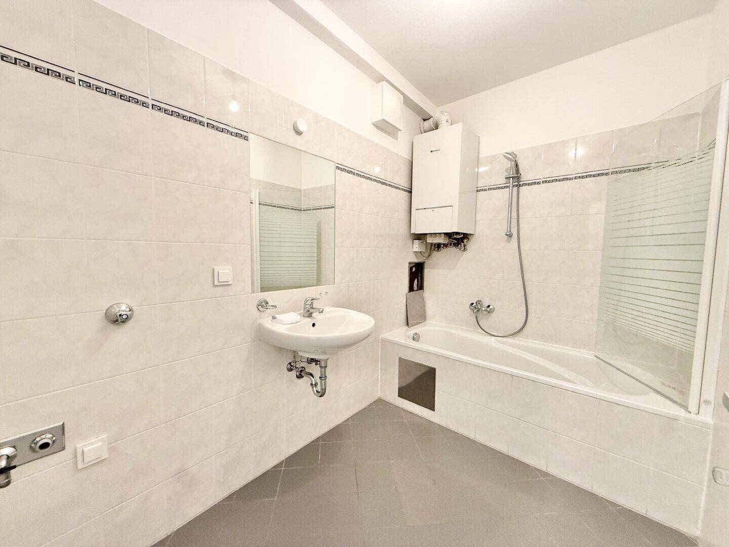 Funktionales Badezimmer mit Badewanne, Dusche, Waschbecken und weißen Fliesen.