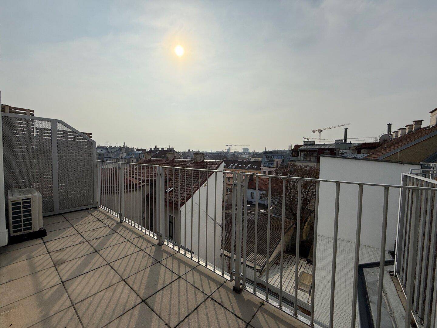 Weitläufige Dachterrasse mit Panoramablick über die Stadt an einem sonnigen Tag.