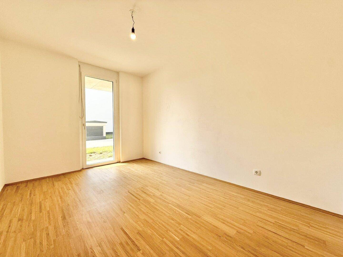 Leerer Raum mit Holzboden und Zugang zu einem Außenbereich, ideal für individuelle Gestaltung.