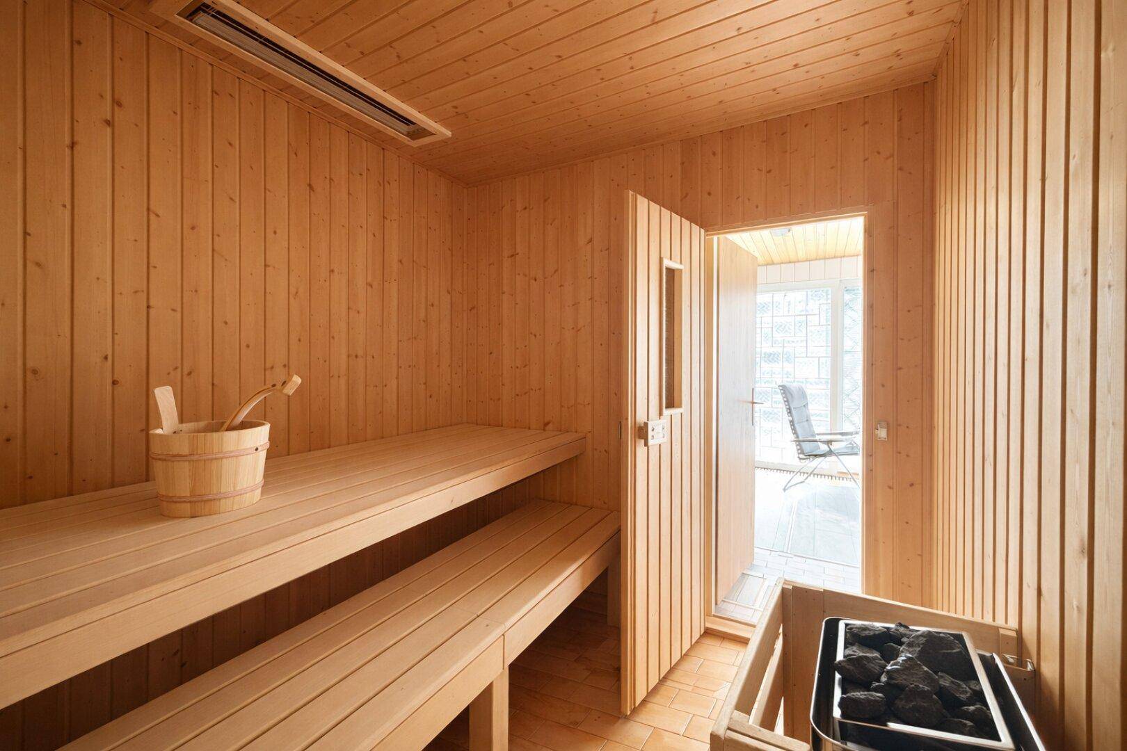 Gemütliche Holzsauna mit Bänken und Saunaofen, bereit zur Entspannung.