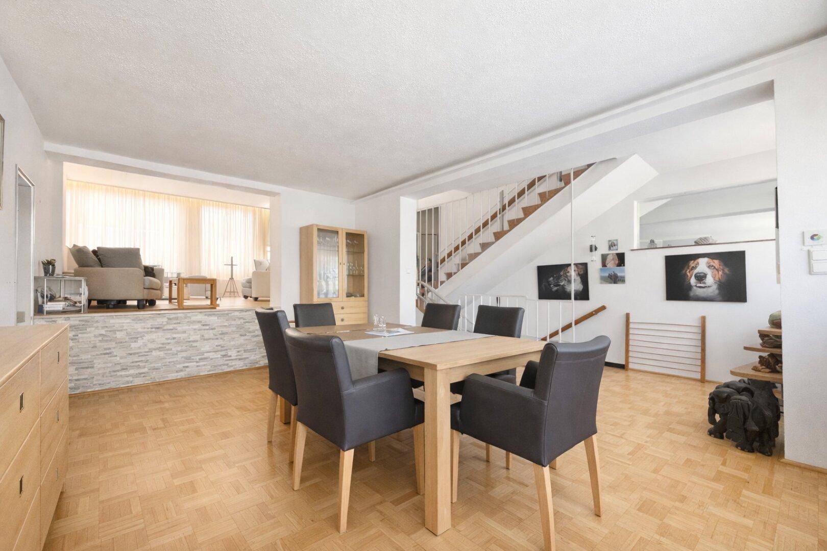 Essbereich mit Holztisch und Stühlen, offen zum Wohnzimmer mit Kamin.