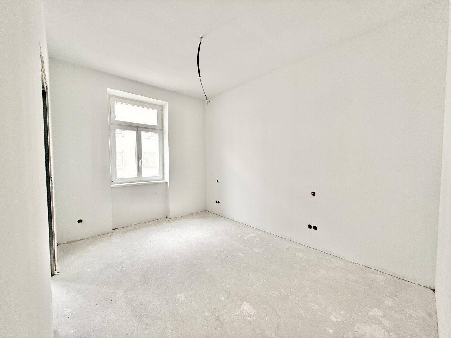 Unmöblierter Raum mit weiß gestrichenen Wänden und einem Fenster, im Rohbauzustand.