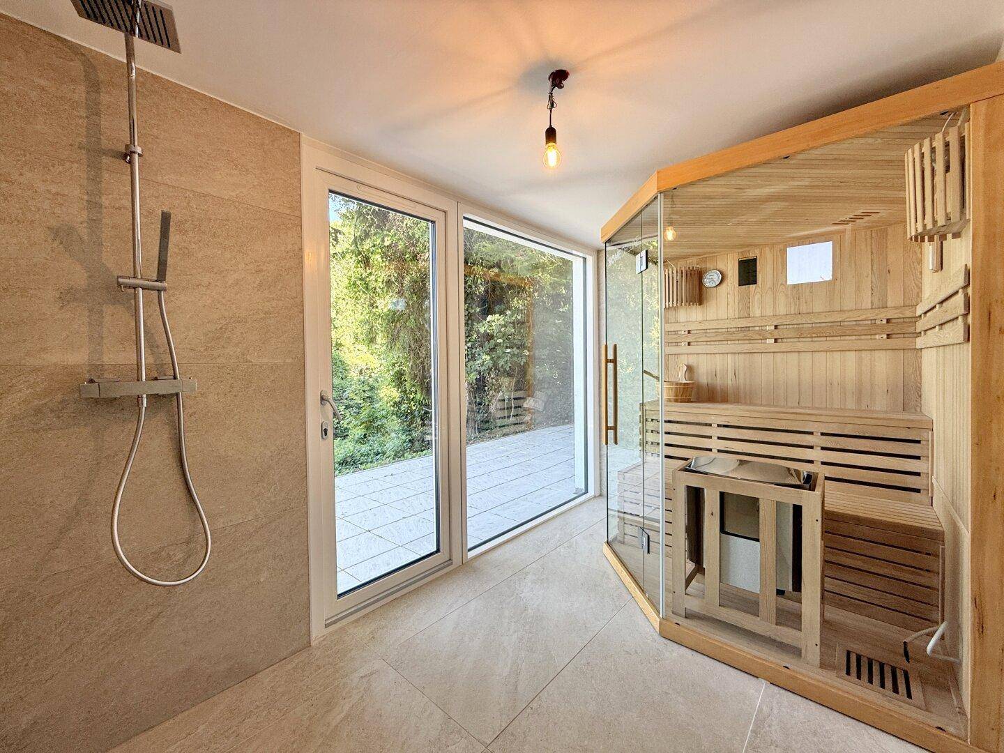 Wellnessbereich mit moderner Sauna, begehbarer Dusche und Blick ins Grüne.