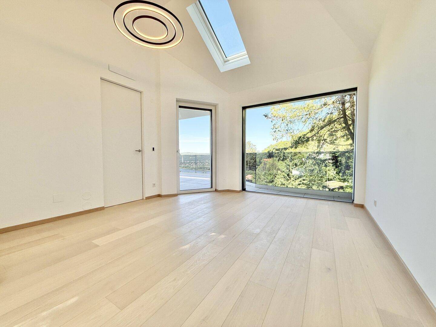Geräumiges Schlafzimmer mit Holzboden, hohen Decken und großen Fenstern mit Weitblick.