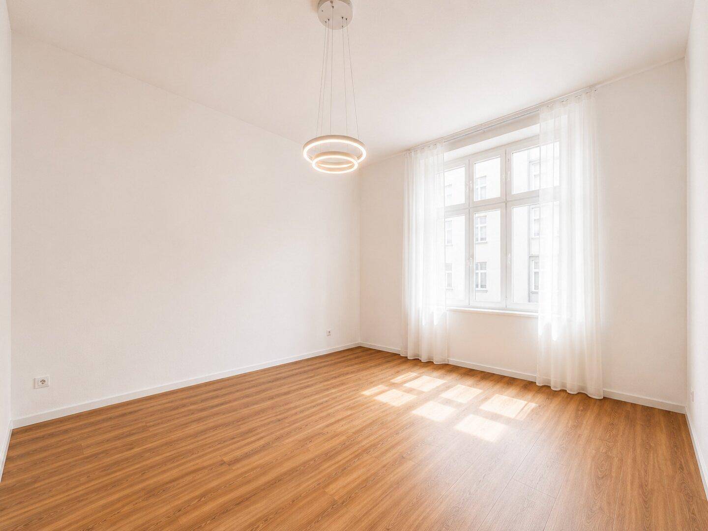 Heller, leerer Raum mit großen Fenstern und Holzboden, bereit zur individuellen Gestaltung.