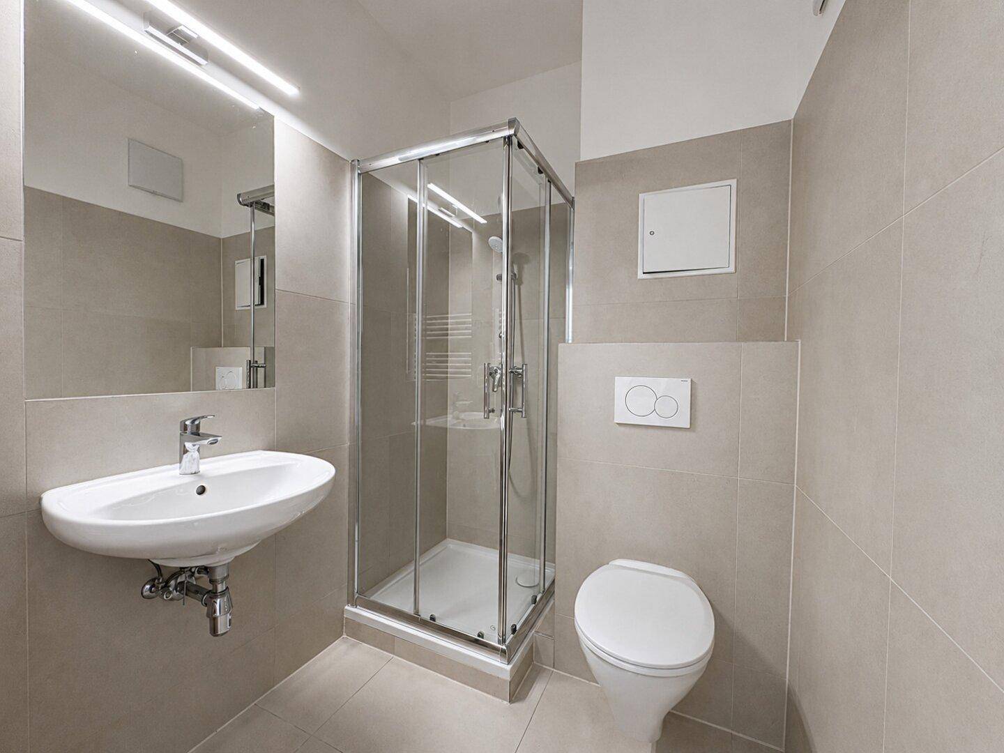 Modernes Badezimmer mit beigefarbenen Fliesen, Duschkabine, Waschbecken und wandhängendem WC.