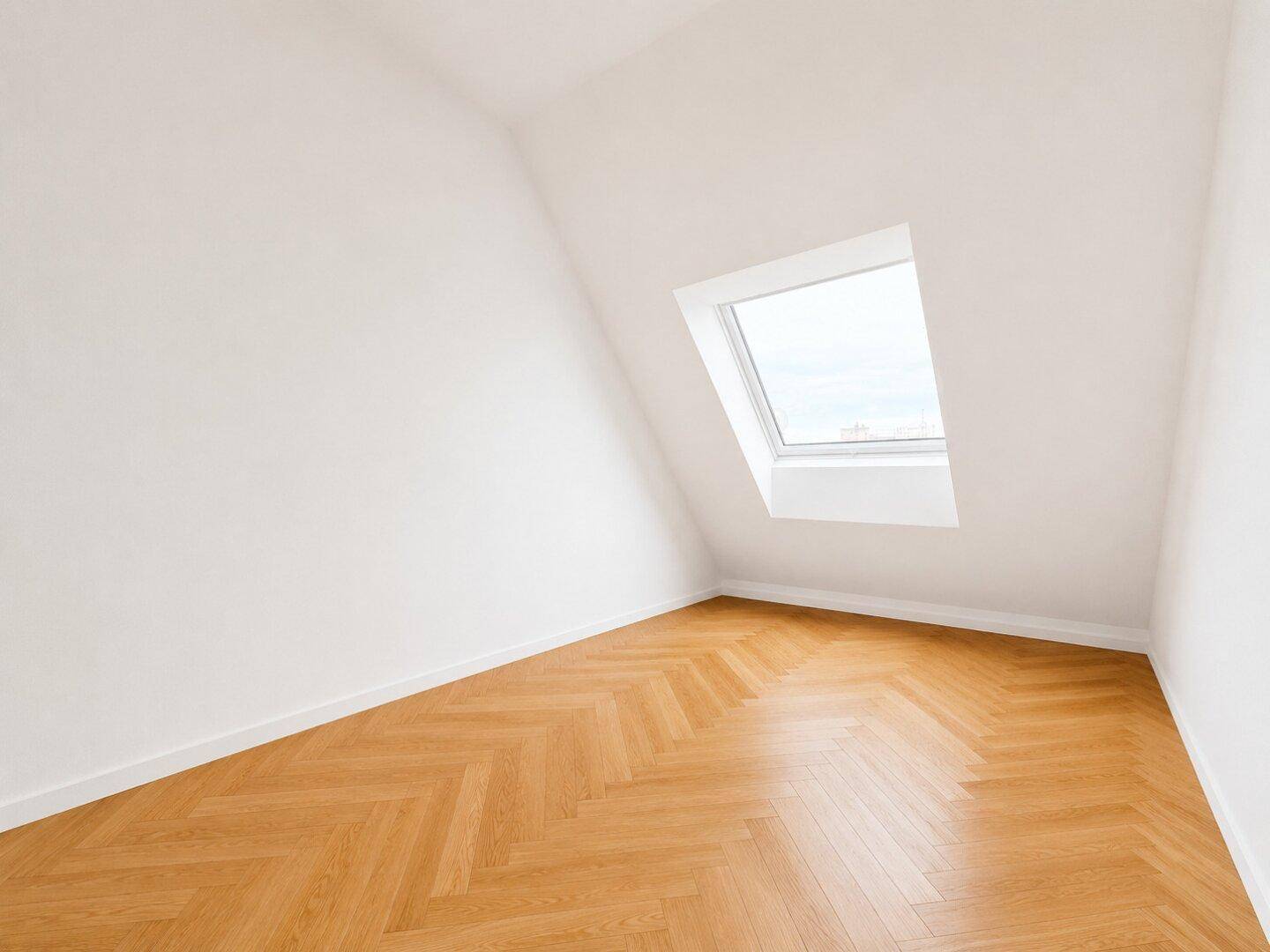 Unmöblierter Raum mit Fischgrätparkett und einem Dachfenster, das viel Tageslicht spendet.