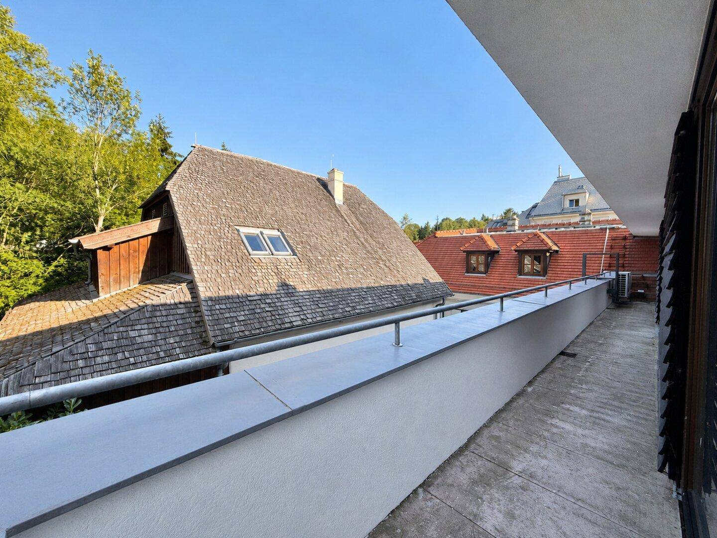 Langer, schmaler Balkon mit Blick auf ein Schindeldach und die umliegende Bebauung.