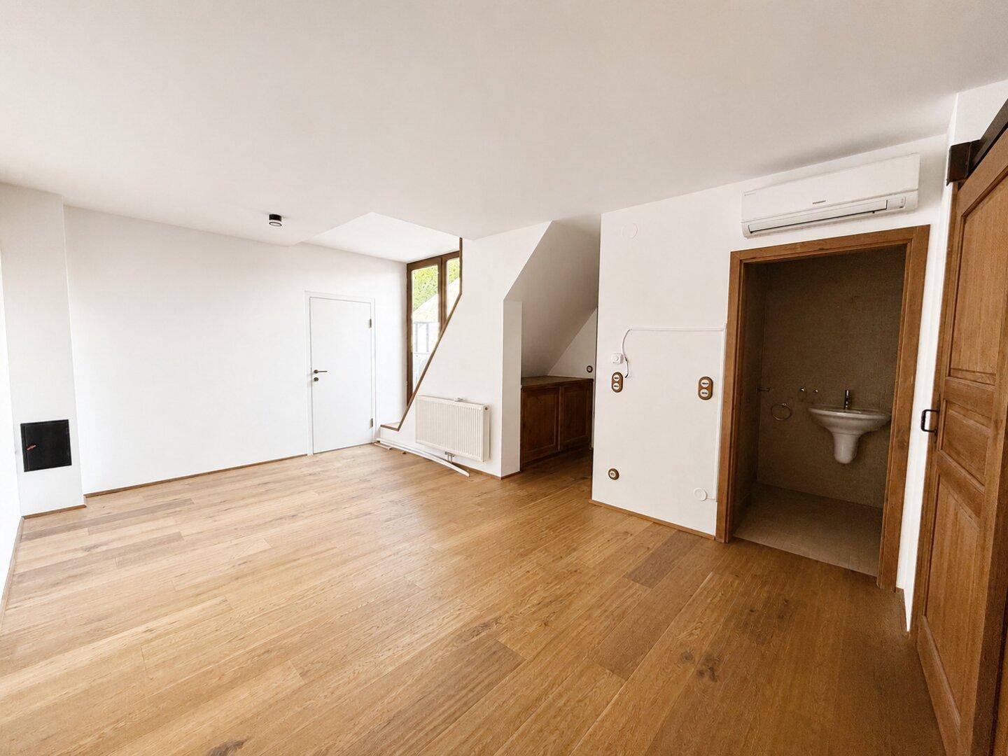 Geräumiger Raum mit Holzboden, Treppe und Zugang zu einem Gäste-WC.