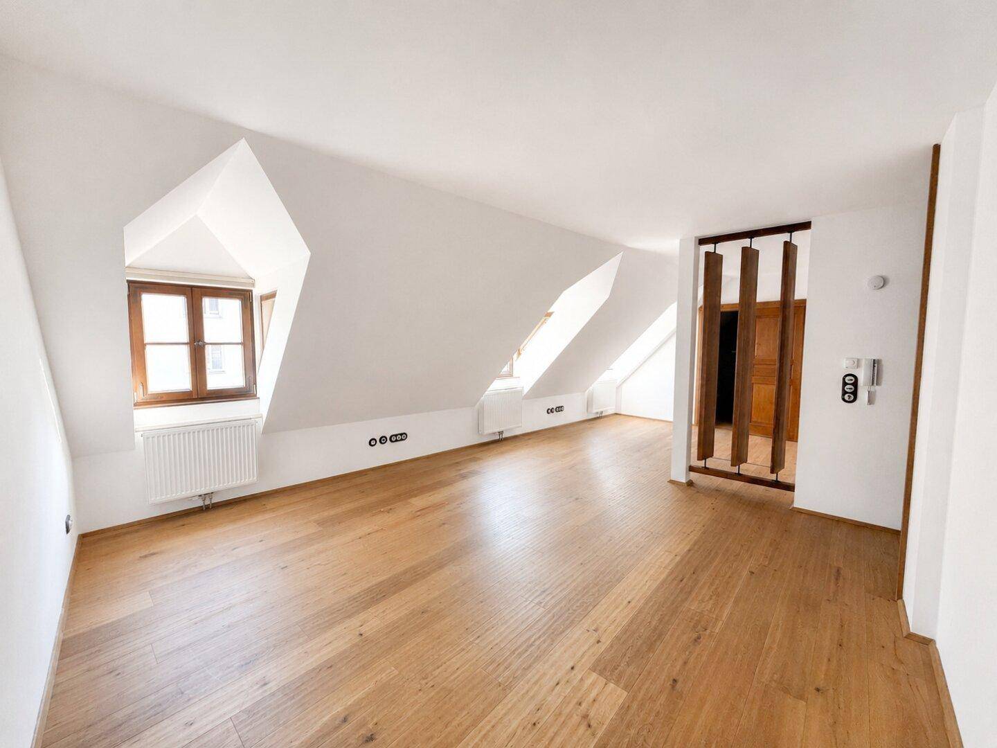 Heller Dachbodenraum mit schrägen Decken, Holzboden und Gaubenfenstern, bereit zur Gestaltung.